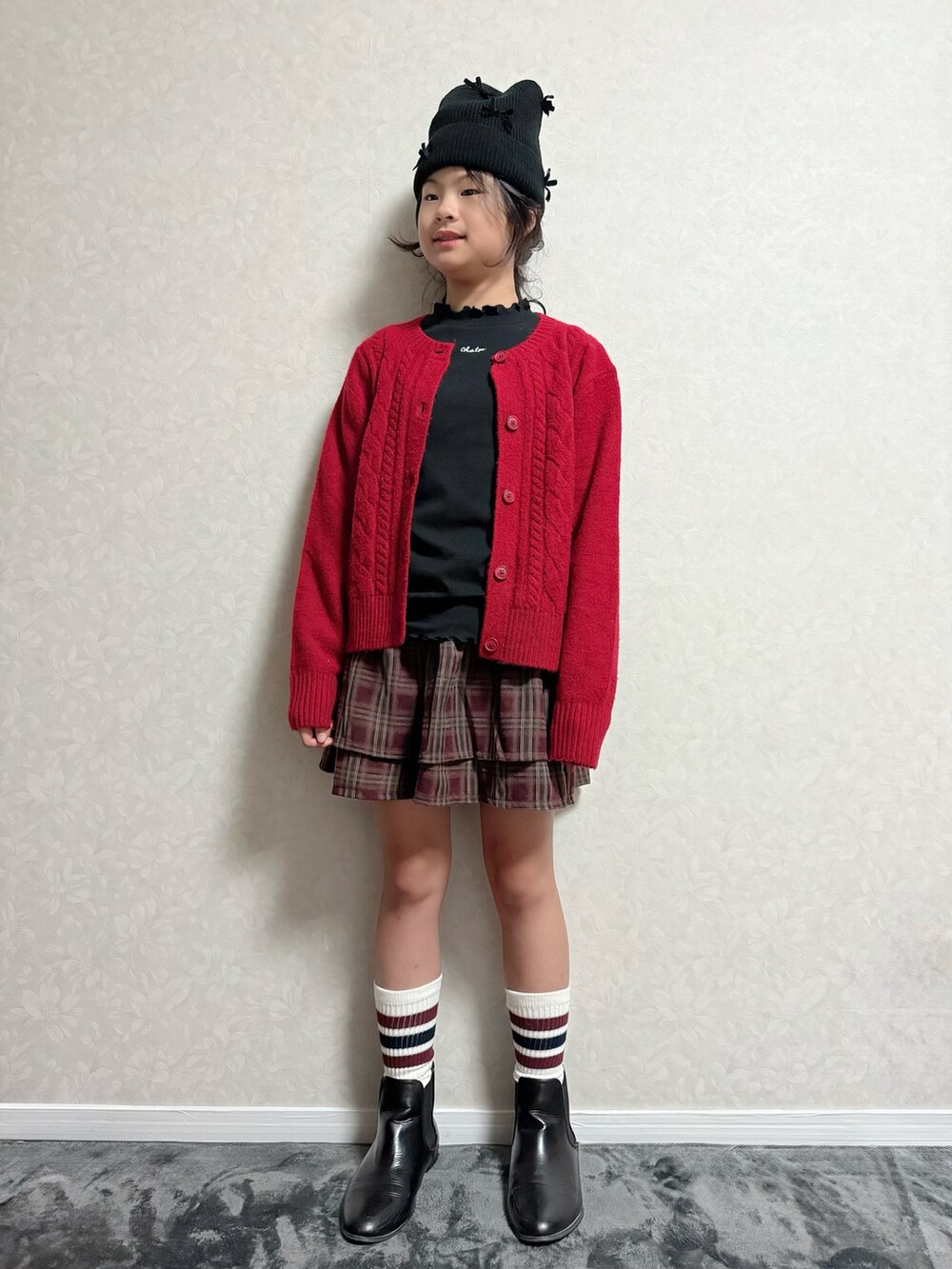 ブラウン系のスカート、ブラック系のブーツ、ブラック系のTシャツ/カットソーを着用したキッズの秋コーディネートの2枚目の写真