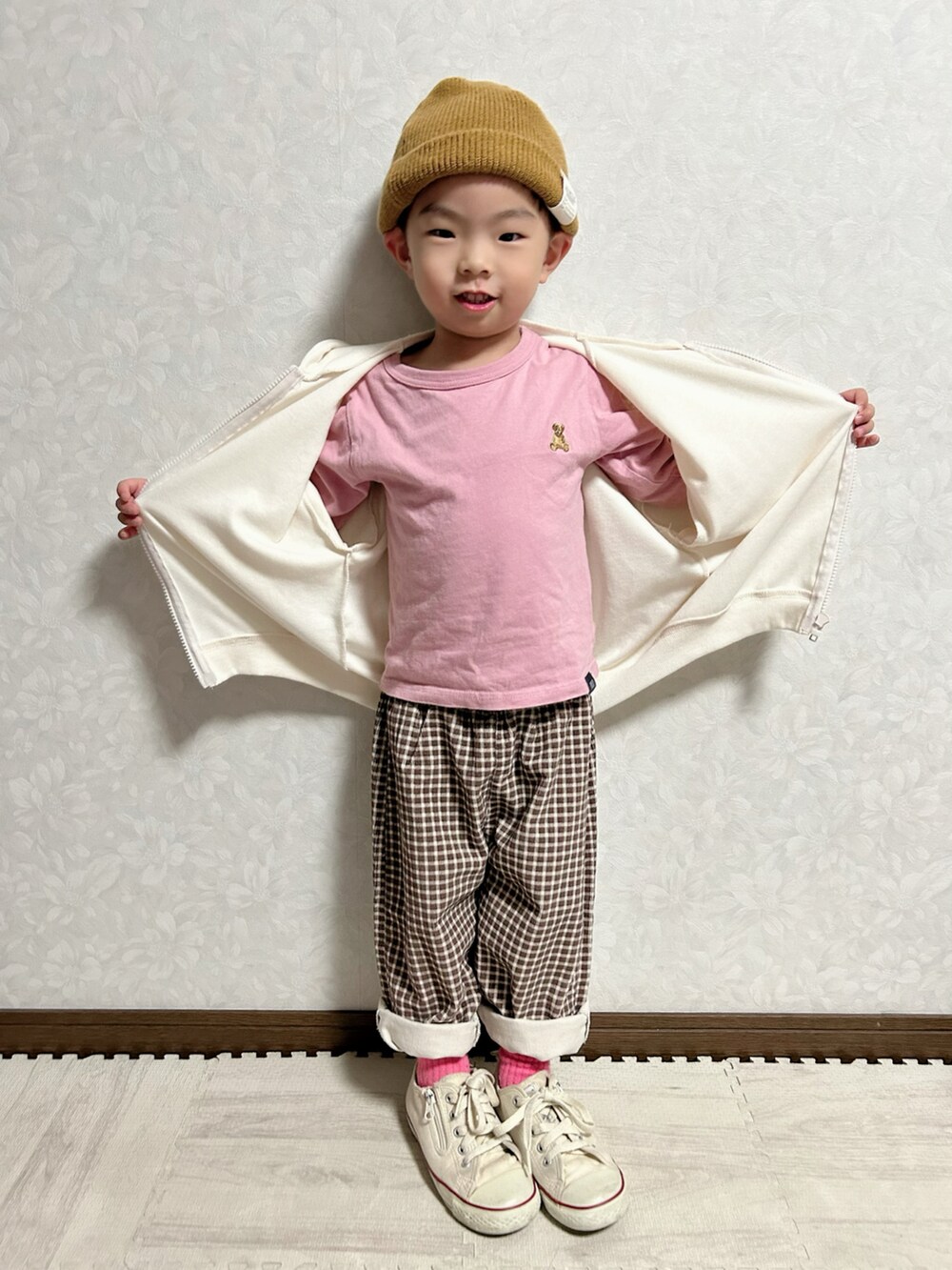 ホワイト系のパーカー、ピンク系のトップス、ブラウン系のパンツを着用したキッズの秋コーディネートの3枚目の写真