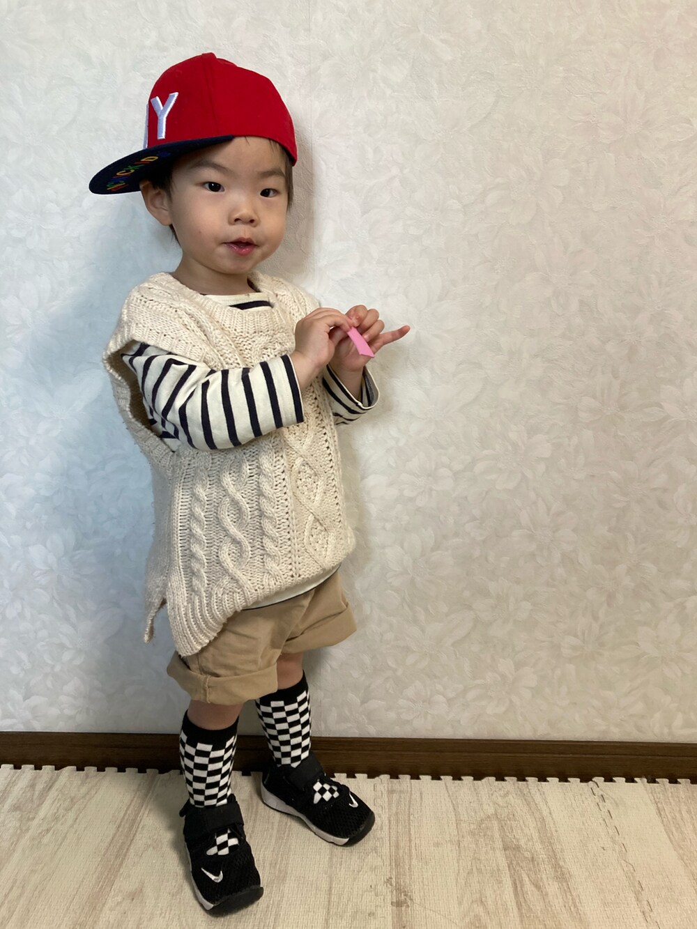 ホワイト系のベスト、ベージュ系のパンツ、ブラック系のスニーカーを着用したキッズの春コーディネートの2枚目の写真