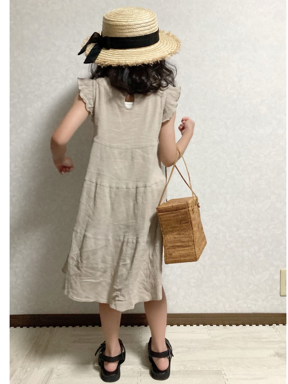 ベージュ系のワンピース、ブラウン系のかごバッグ、ブラック系のサンダルを着用したキッズの夏コーディネートの4枚目の写真