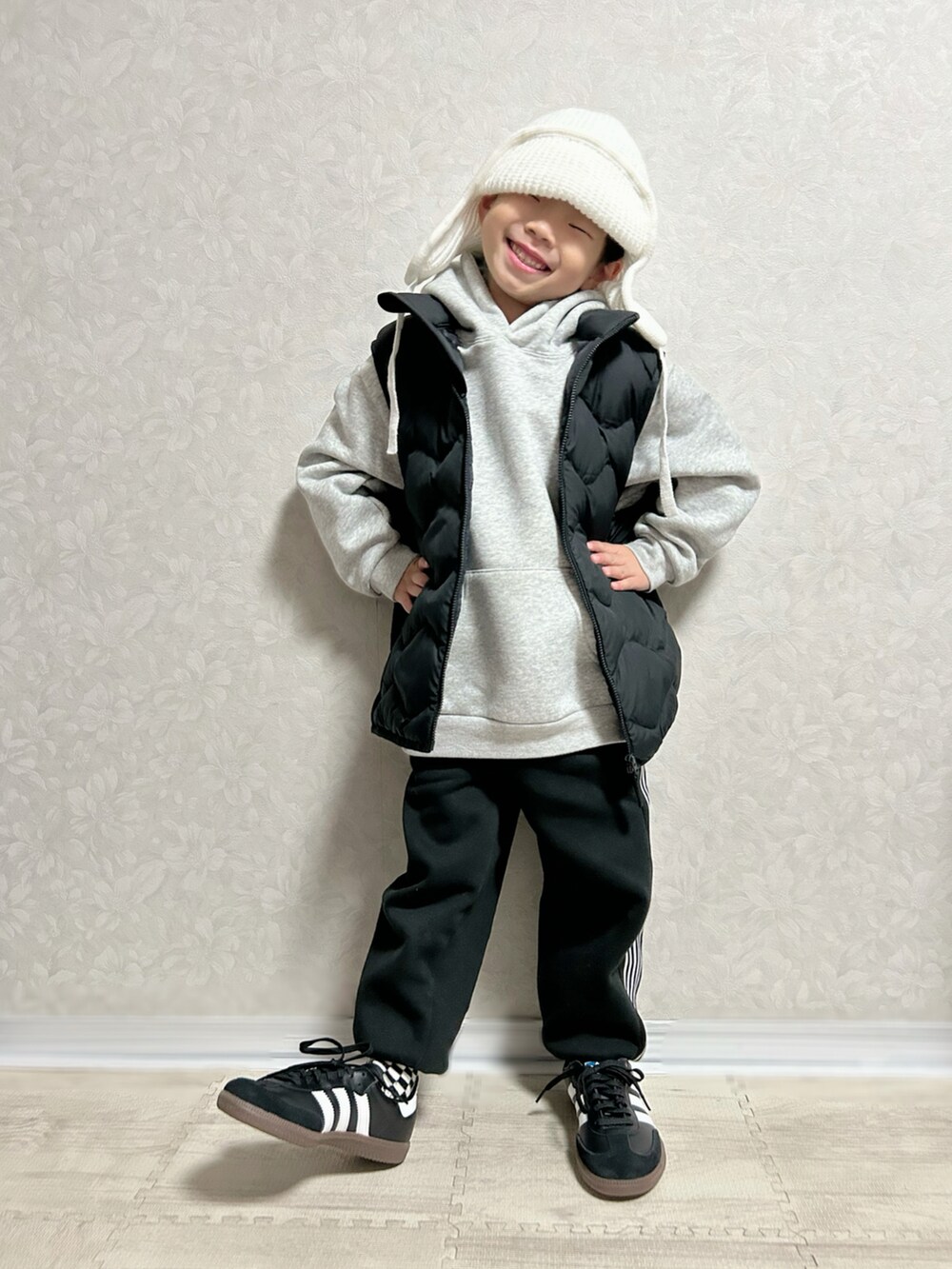 グレー系のパーカー、ブラック系のダウンベスト、ブラック系のセットアップを着用したキッズの冬コーディネートの4枚目の写真