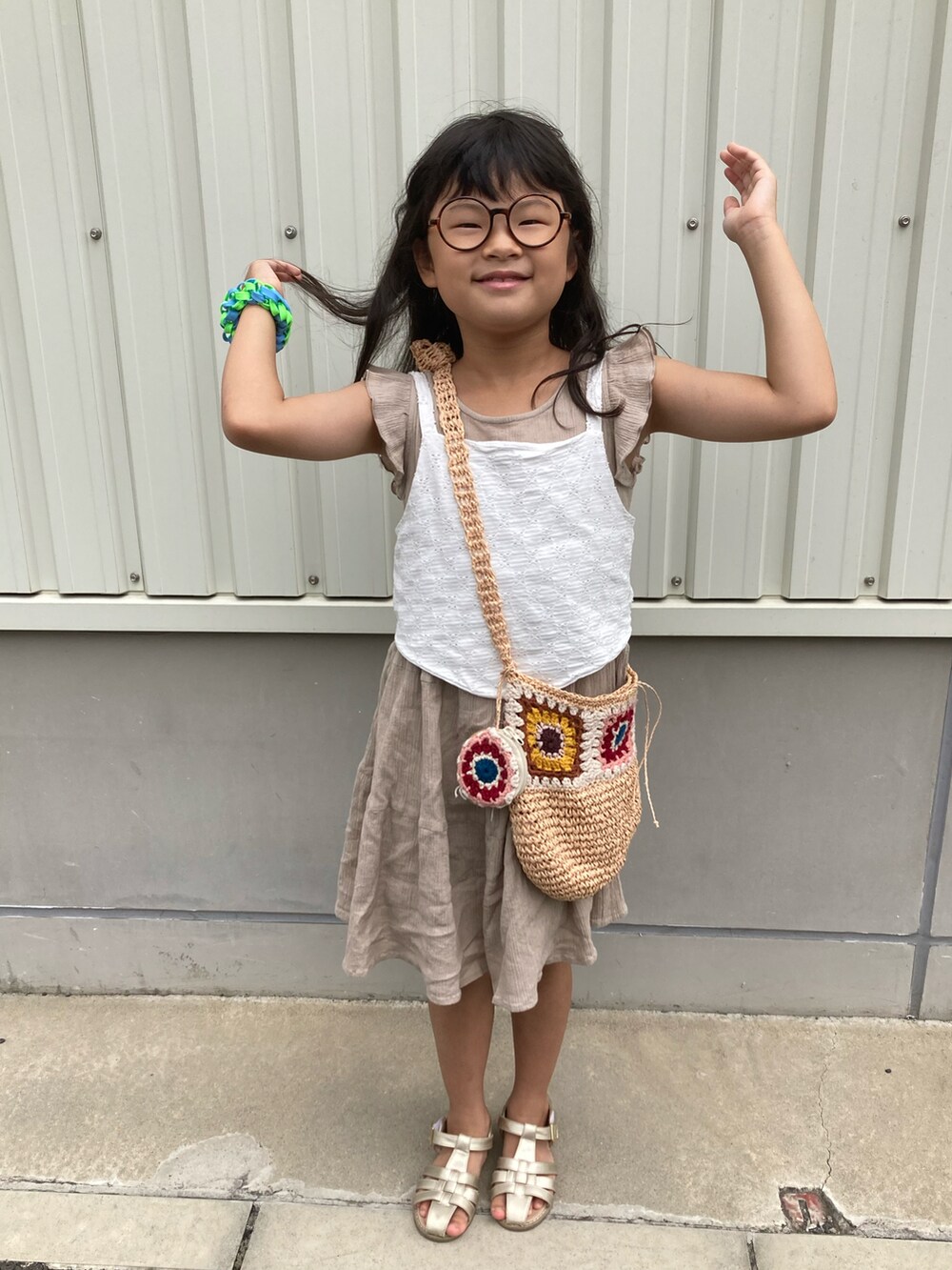 ベージュ系のワンピース、ホワイト系のキャミソール、ブラウン系のショルダーバッグを着用したキッズの夏コーディネートの3枚目の写真