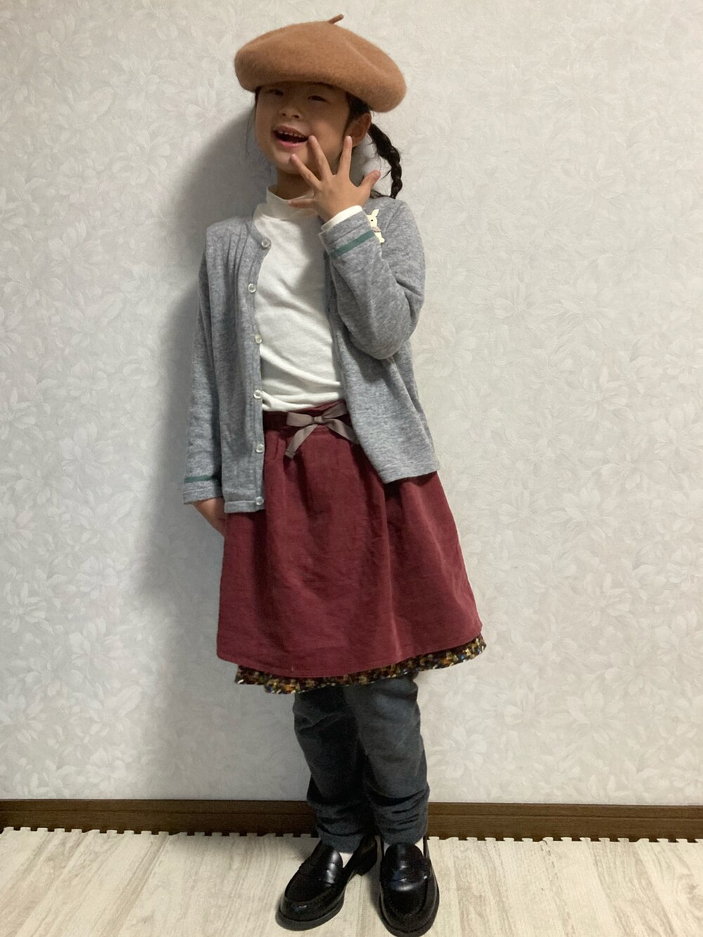 ホワイト系のTシャツ/カットソー、グレー系のカーディガン/ボレロ、パープル系のスカートを着用したキッズの冬コーディネートの3枚目の写真