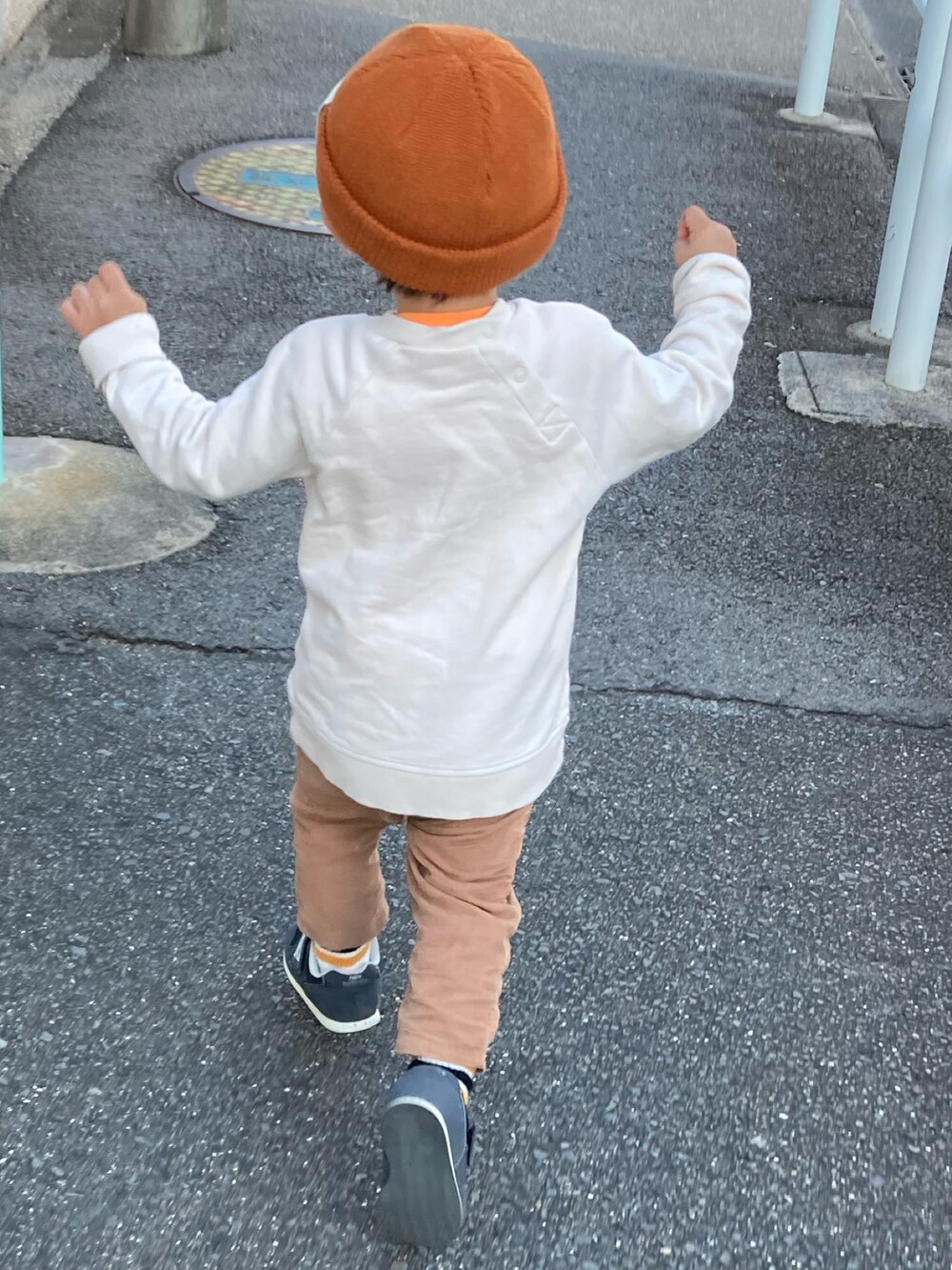 オレンジ系のタンクトップ、ベージュ系のスウェット、ブラウン系のパンツを着用したキッズの秋コーディネートの3枚目の写真