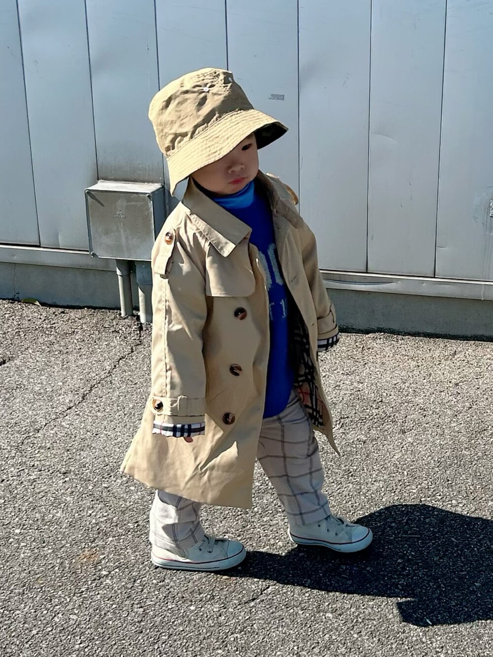 ベージュ系のトレンチコート、ブルー系のニット/セーター、ブルー系のTシャツ/カットソーを着用したキッズの冬コーディネートの3枚目の写真