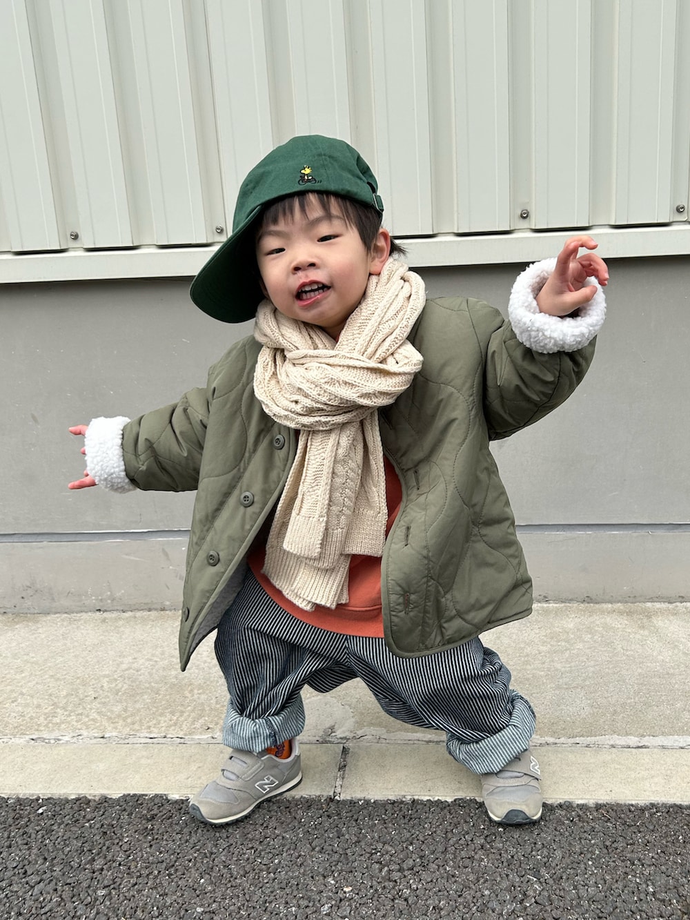 オレンジ系のスウェット、グリーン系のノーカラージャケット、ブルー系のデニムパンツを着用したキッズの冬コーディネートの2枚目の写真