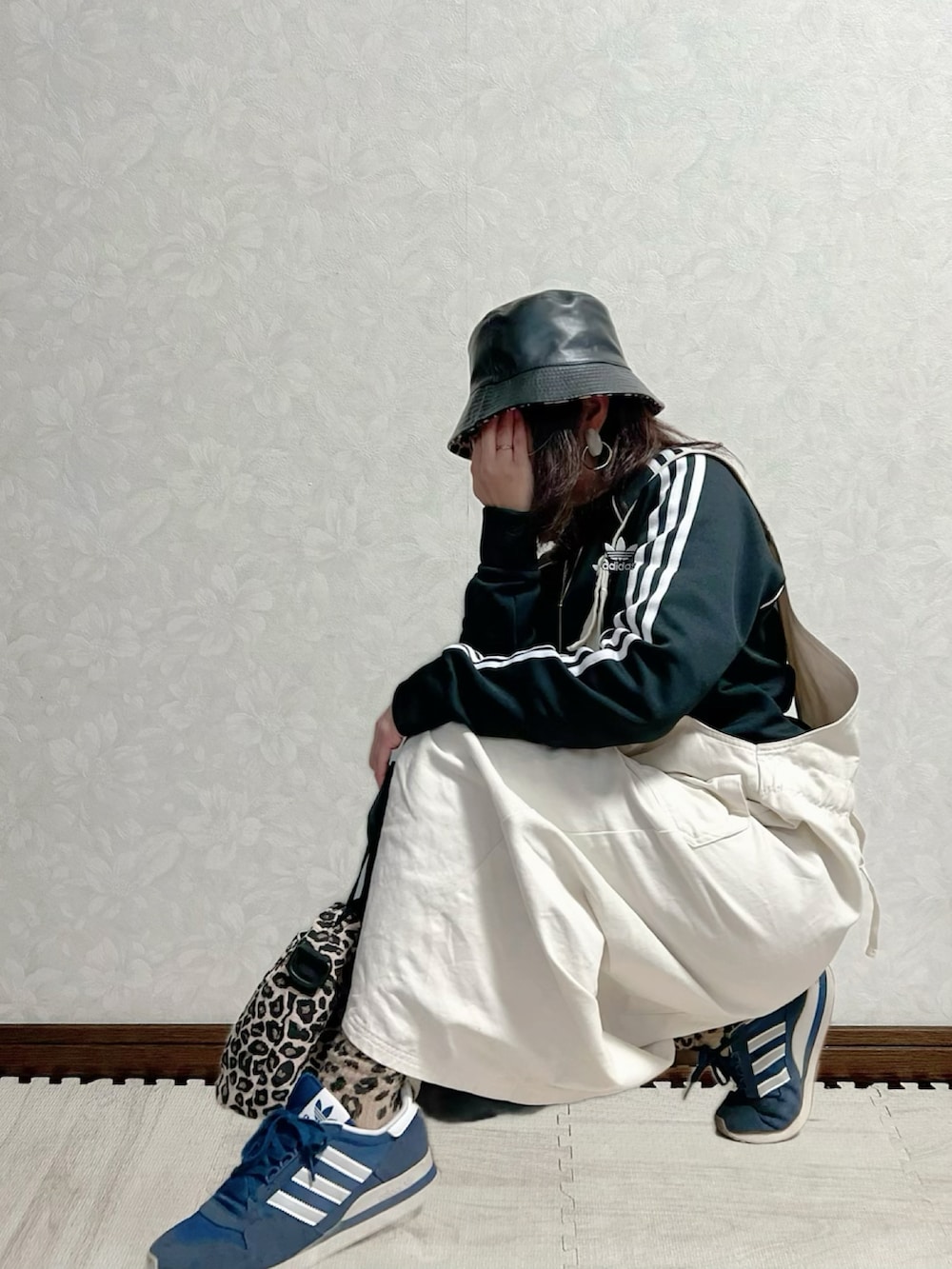 ブラック系のブルゾン、ホワイト系のジャンパースカート、ブラウン系のショルダーバッグを着用したレディースの冬コーディネートの2枚目の写真