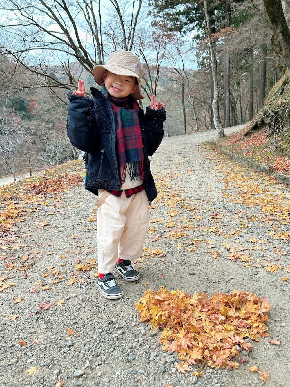 ベージュ系のチノパンツ、ブラック系のバックパック/リュック、ブラック系のスニーカーを着用したキッズの冬コーディネートの3枚目の写真