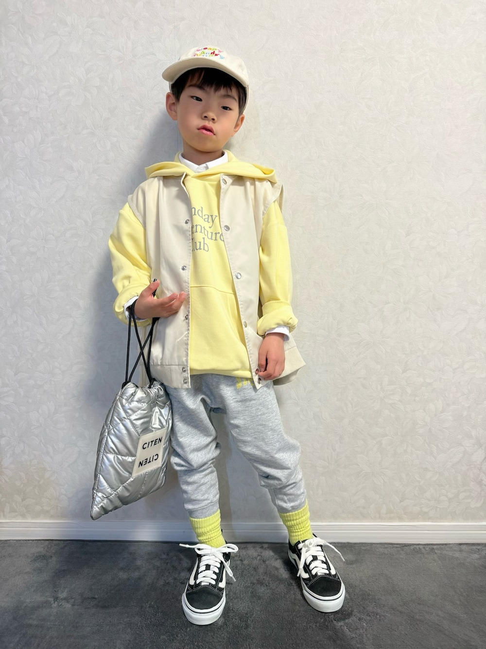 ベージュ系のベスト、グレー系のスウェットパンツ、シルバー系のショルダーバッグを着用したキッズの冬コーディネートの2枚目の写真