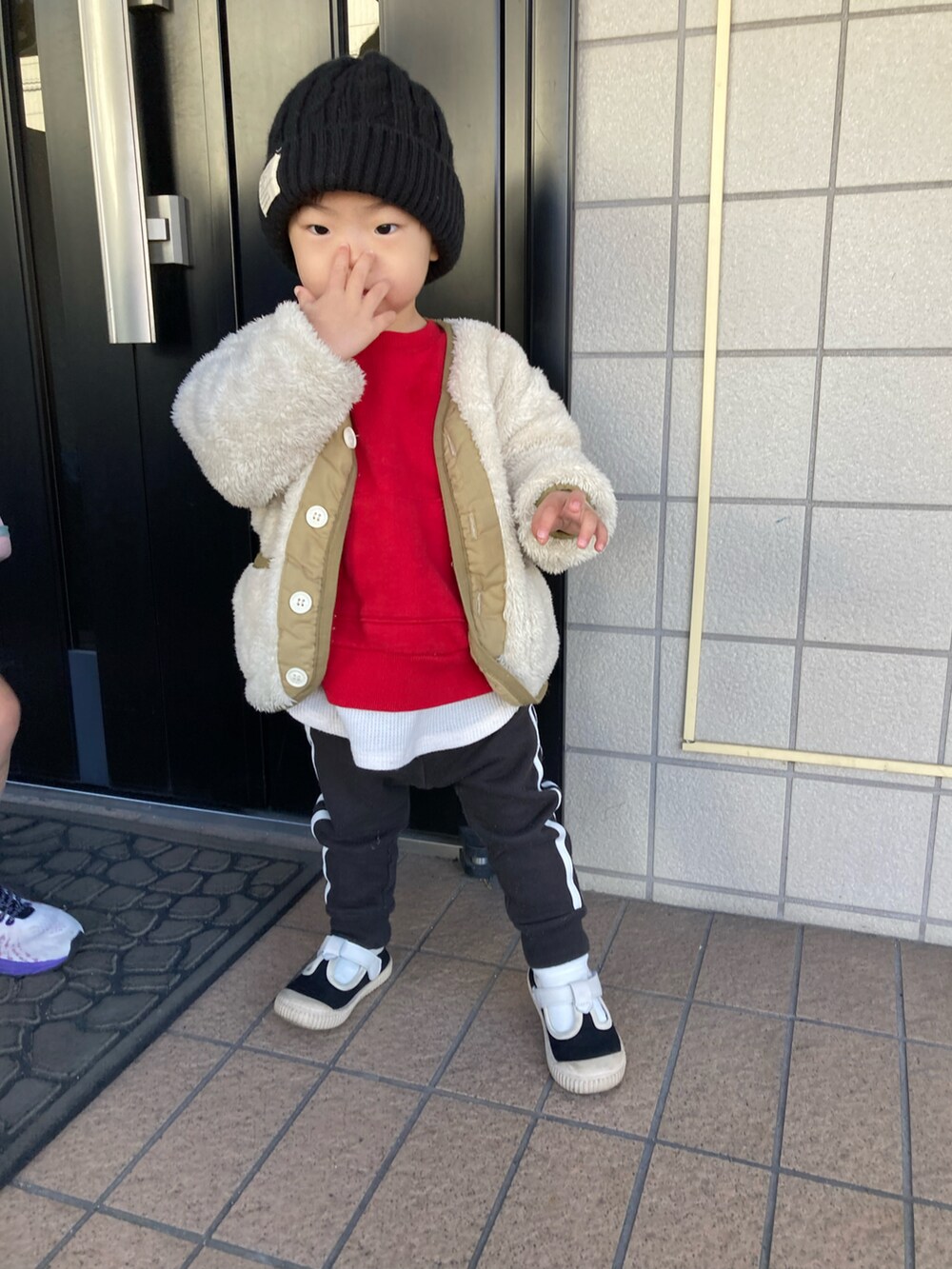 ベージュ系のノーカラージャケット、レッド系のスウェット、ブラック系のスウェットパンツを着用したキッズの冬コーディネートの2枚目の写真