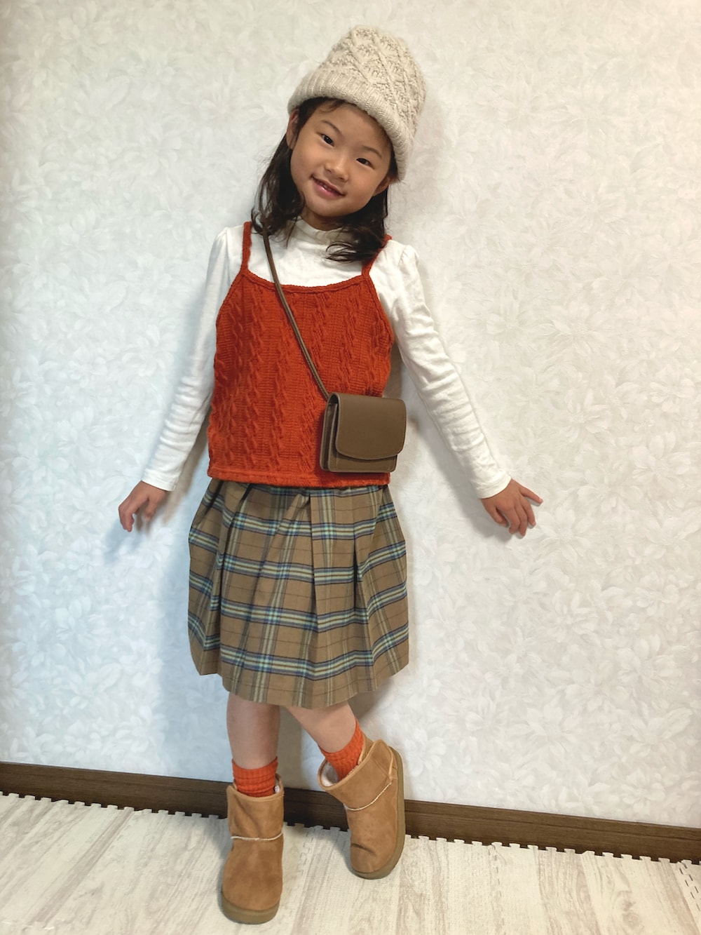 ホワイト系のTシャツ/カットソー、オレンジ系のベスト、ブラウン系のスカートを着用したキッズの秋コーディネートの4枚目の写真