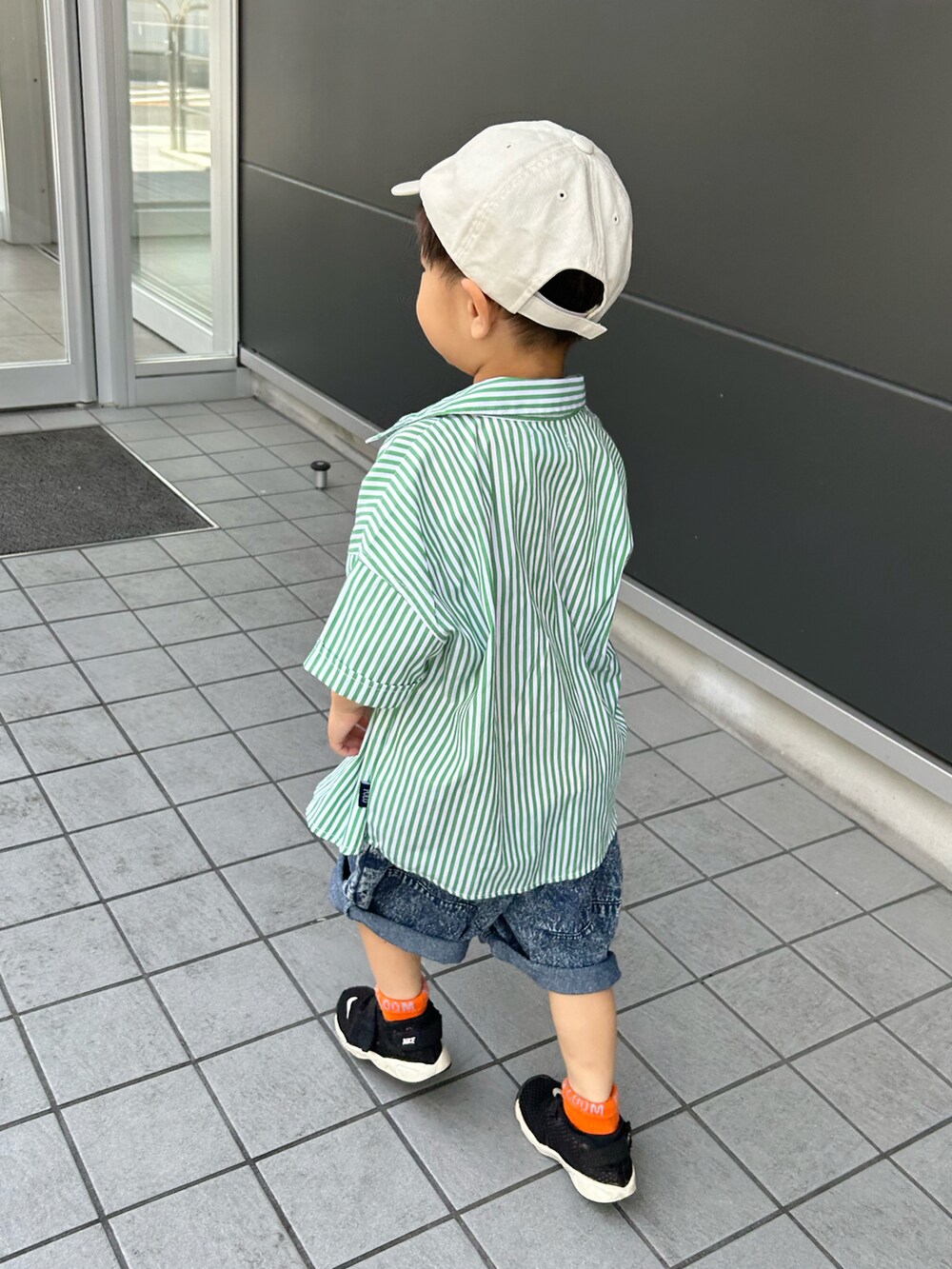 グリーン系のシャツ/ブラウス、オレンジ系のタンクトップ、ブルー系のデニムパンツを着用したキッズの夏コーディネートの3枚目の写真