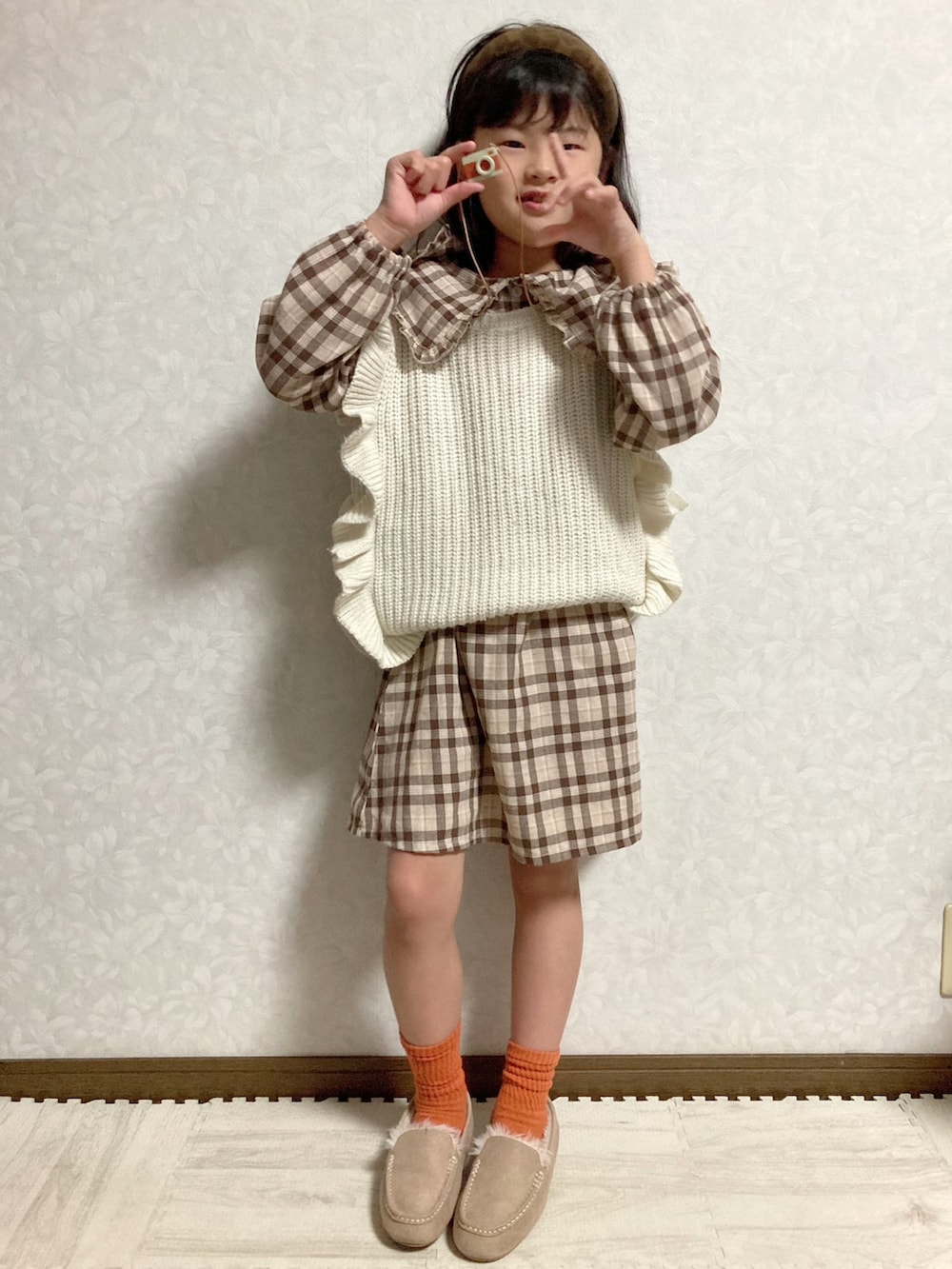 ブラウン系のシャツワンピース、ベージュ系のベスト、グリーン系のスカートを着用したキッズの秋コーディネートの2枚目の写真