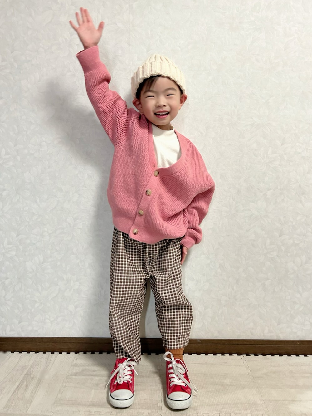 ホワイト系のニット/セーター、ピンク系のカーディガン/ボレロ、ブラウン系のパンツを着用したキッズの冬コーディネートの2枚目の写真