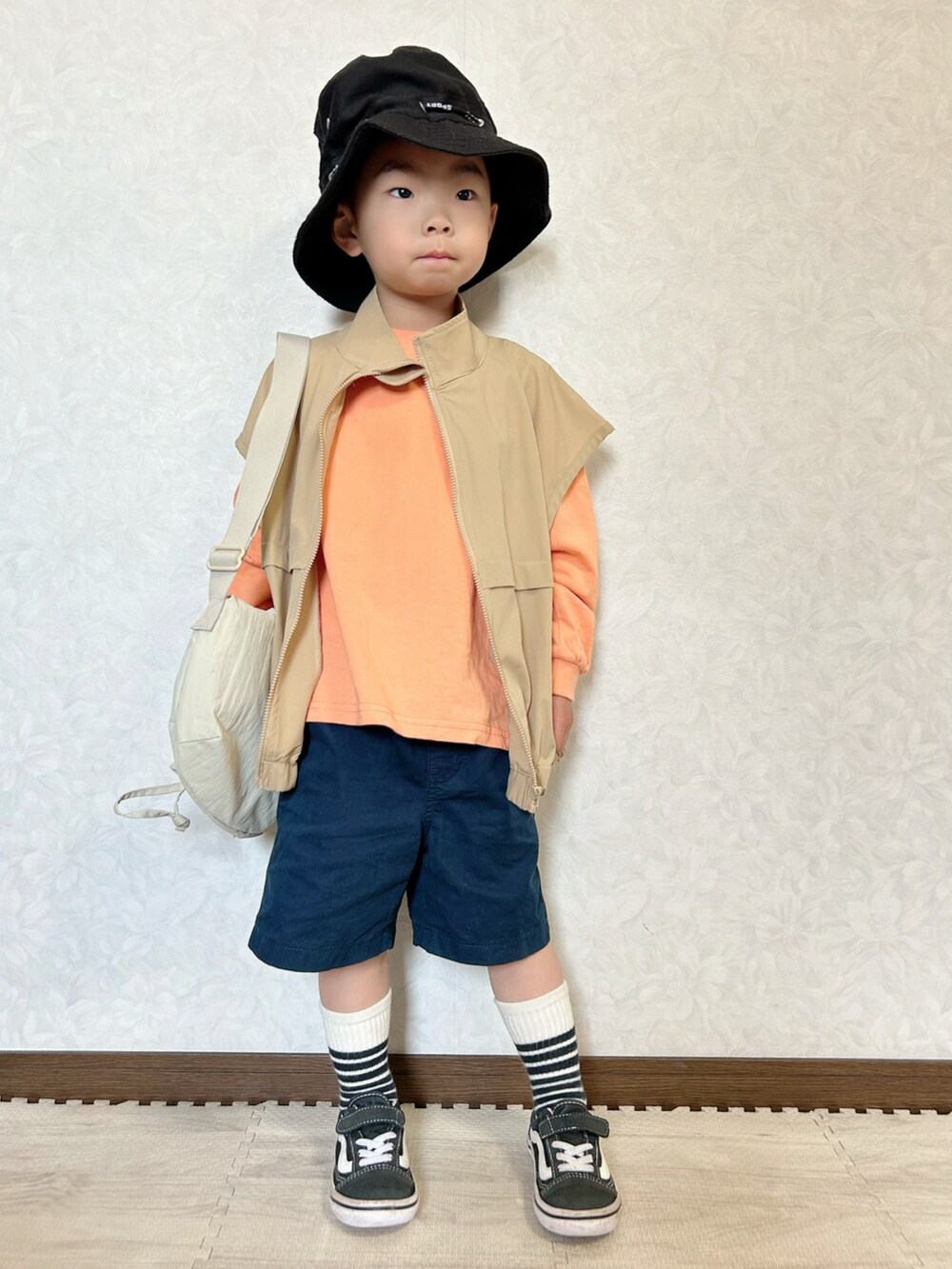 オレンジ系のTシャツ/カットソー、ホワイト系のショルダーバッグ、ベージュ系のベストを着用したキッズの春コーディネートの3枚目の写真