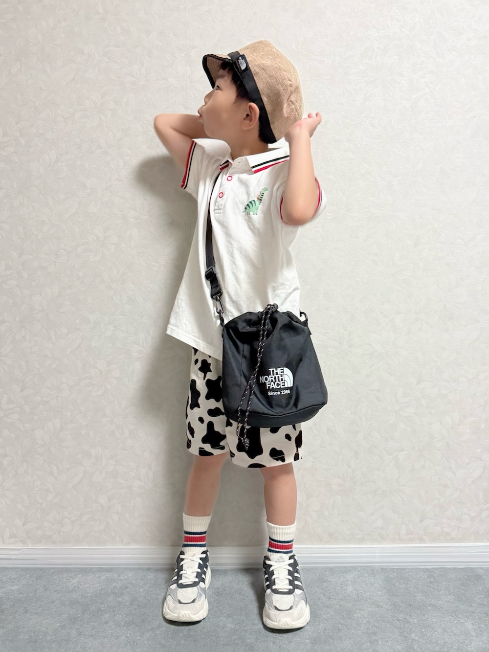 ホワイト系のポロシャツ、ブラック系のショルダーバッグ、ホワイト系のスニーカーを着用したキッズの秋コーディネートの3枚目の写真