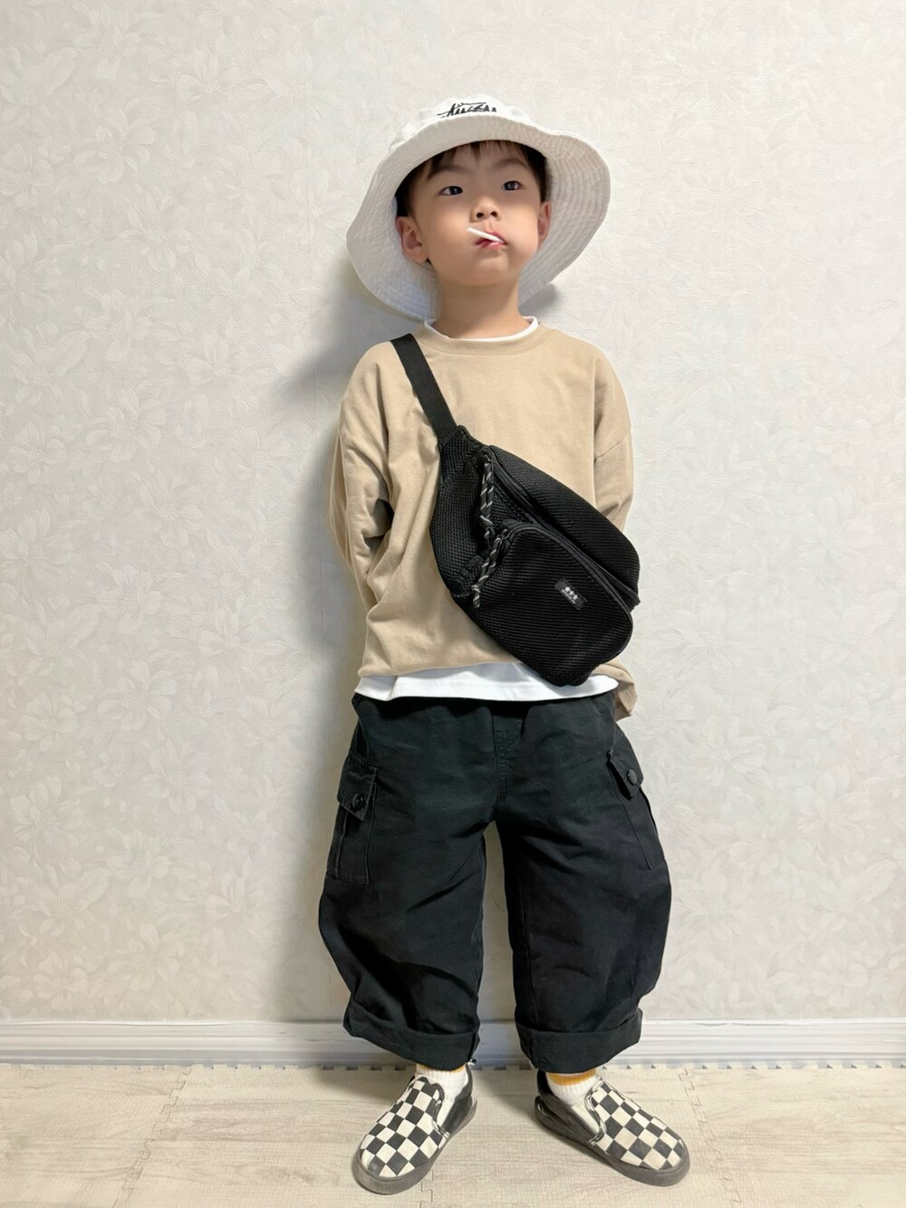 ベージュ系のTシャツ/カットソー、ブラック系のベスト、ブラック系のカーゴパンツを着用したキッズの春コーディネートの2枚目の写真