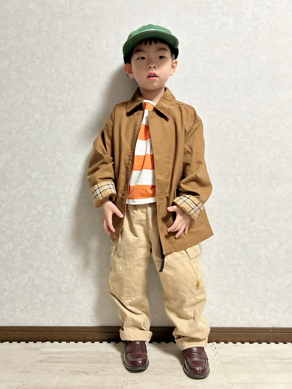 ブラウン系のブルゾン、グリーン系のショルダーバッグ、オレンジ系のTシャツ/カットソーを着用したキッズの秋コーディネートの2枚目の写真