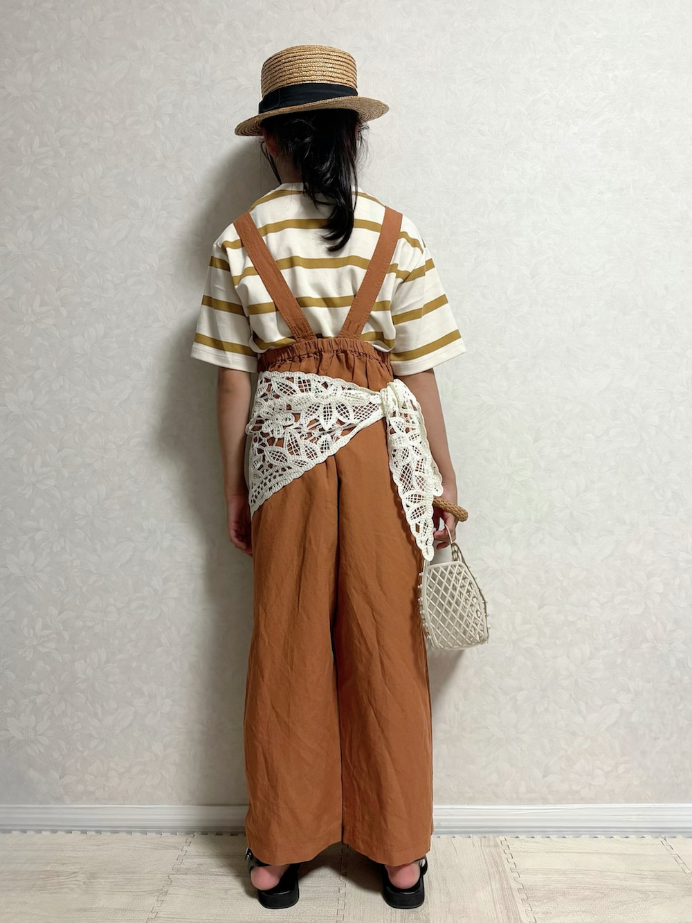 ブラック系のサンダル、ブラウン系のサロペット/オーバーオール、ホワイト系のトートバッグを着用したキッズの夏コーディネートの4枚目の写真