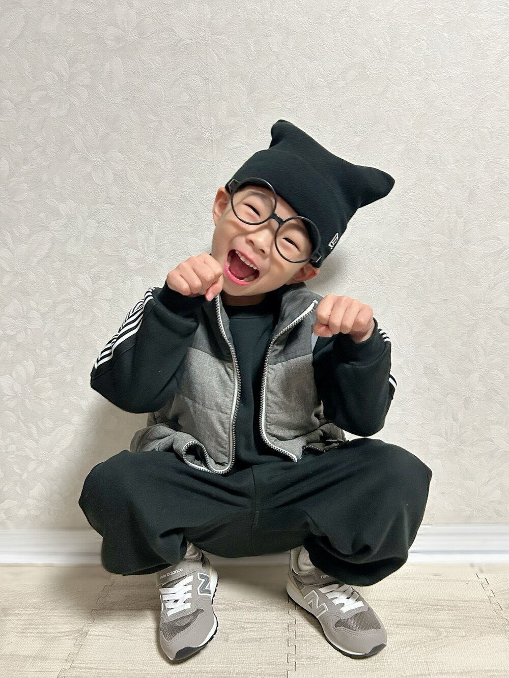 ホワイト系のTシャツ/カットソー、ブラック系のセットアップ、グレー系のダウンベストを着用したキッズの冬コーディネートの5枚目の写真