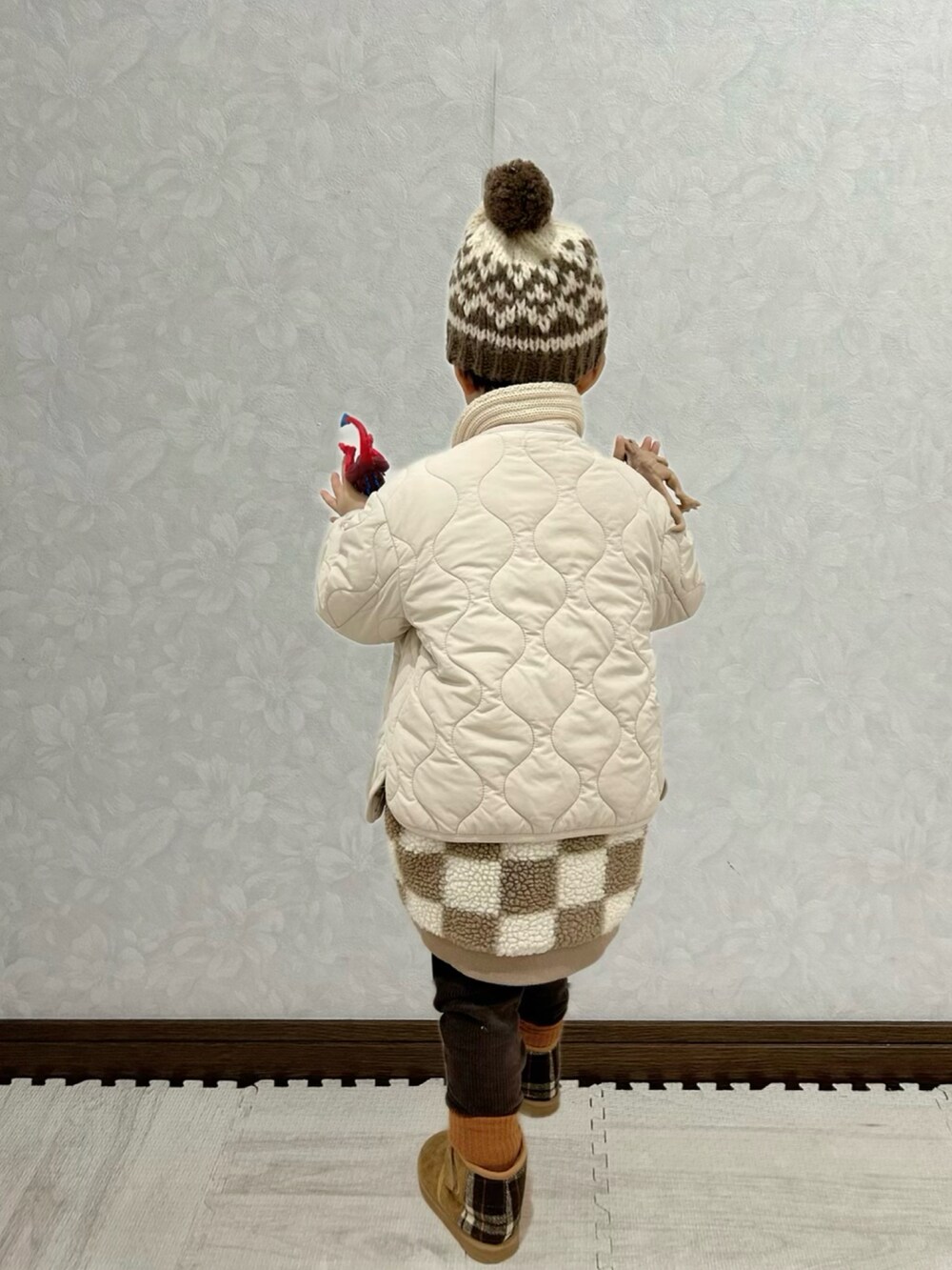 ブラウン系のベスト、ホワイト系のノーカラージャケット、ブラウン系のブーツを着用したキッズの冬コーディネートの4枚目の写真