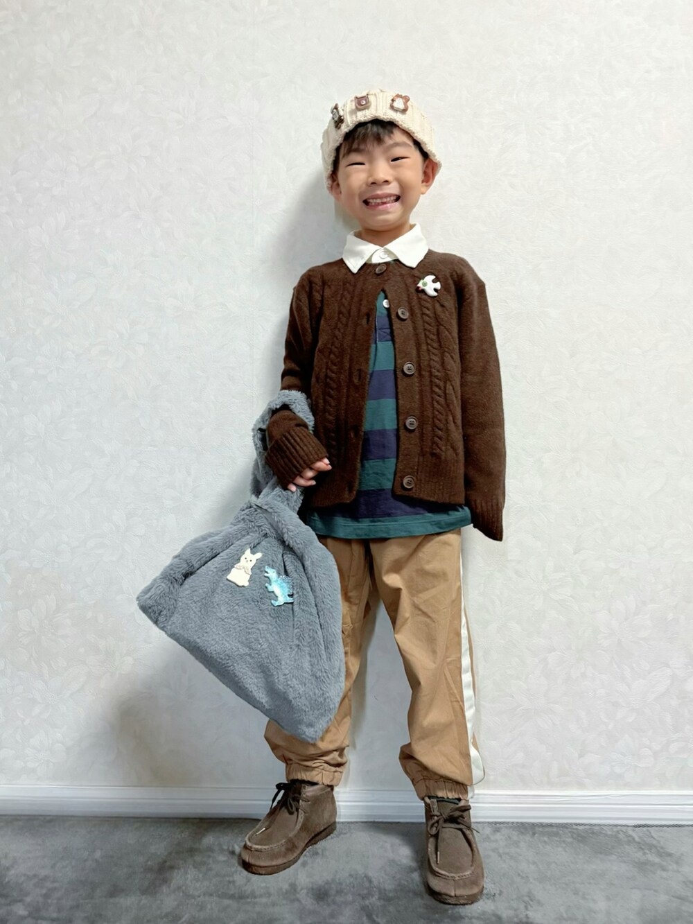 ブラウン系のカーディガン/ボレロ、グリーン系のTシャツ/カットソー、ベージュ系のパンツを着用したキッズの秋コーディネートの2枚目の写真