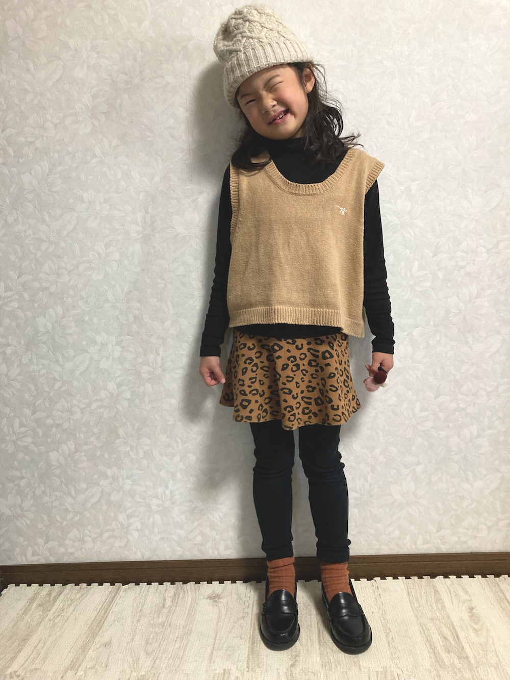 ブラック系のニット/セーター、ベージュ系のベスト、ブラウン系のスカートを着用したキッズの冬コーディネートの4枚目の写真