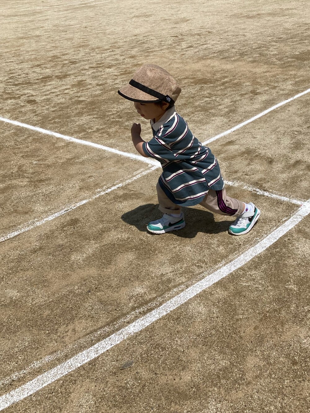 グリーン系のポロシャツ、ベージュ系のその他パンツ、ホワイト系のスニーカーを着用したキッズの春コーディネートの4枚目の写真