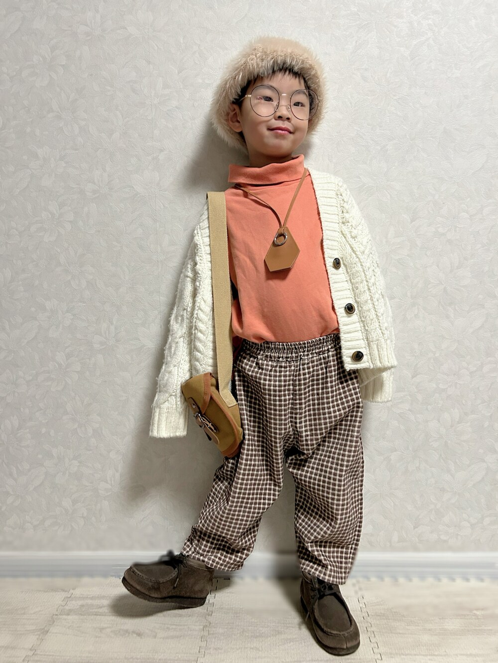 オレンジ系のスウェット、ホワイト系のカーディガン/ボレロ、ブラウン系のショルダーバッグを着用したキッズの冬コーディネートの4枚目の写真
