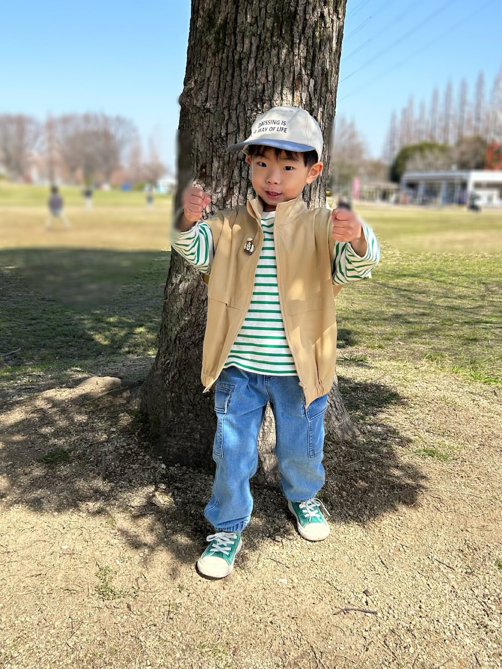 グリーン系のTシャツ/カットソー、ベージュ系のベスト、ブルー系のデニムパンツを着用したキッズの春コーディネートの5枚目の写真