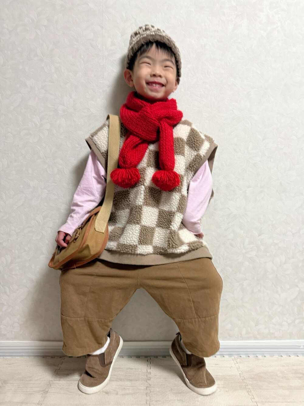 ピンク系のTシャツ/カットソー、ブラウン系のベスト、ブラウン系のショルダーバッグを着用したキッズの冬コーディネートの2枚目の写真