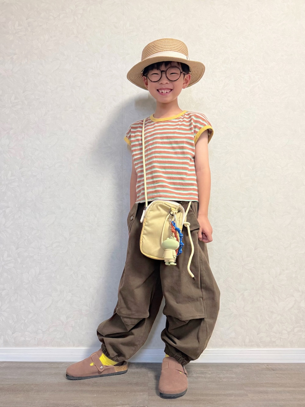ブラウン系のTシャツ/カットソー、ブラウン系のカーゴパンツ、イエロー系のショルダーバッグを着用したキッズの夏コーディネートの2枚目の写真