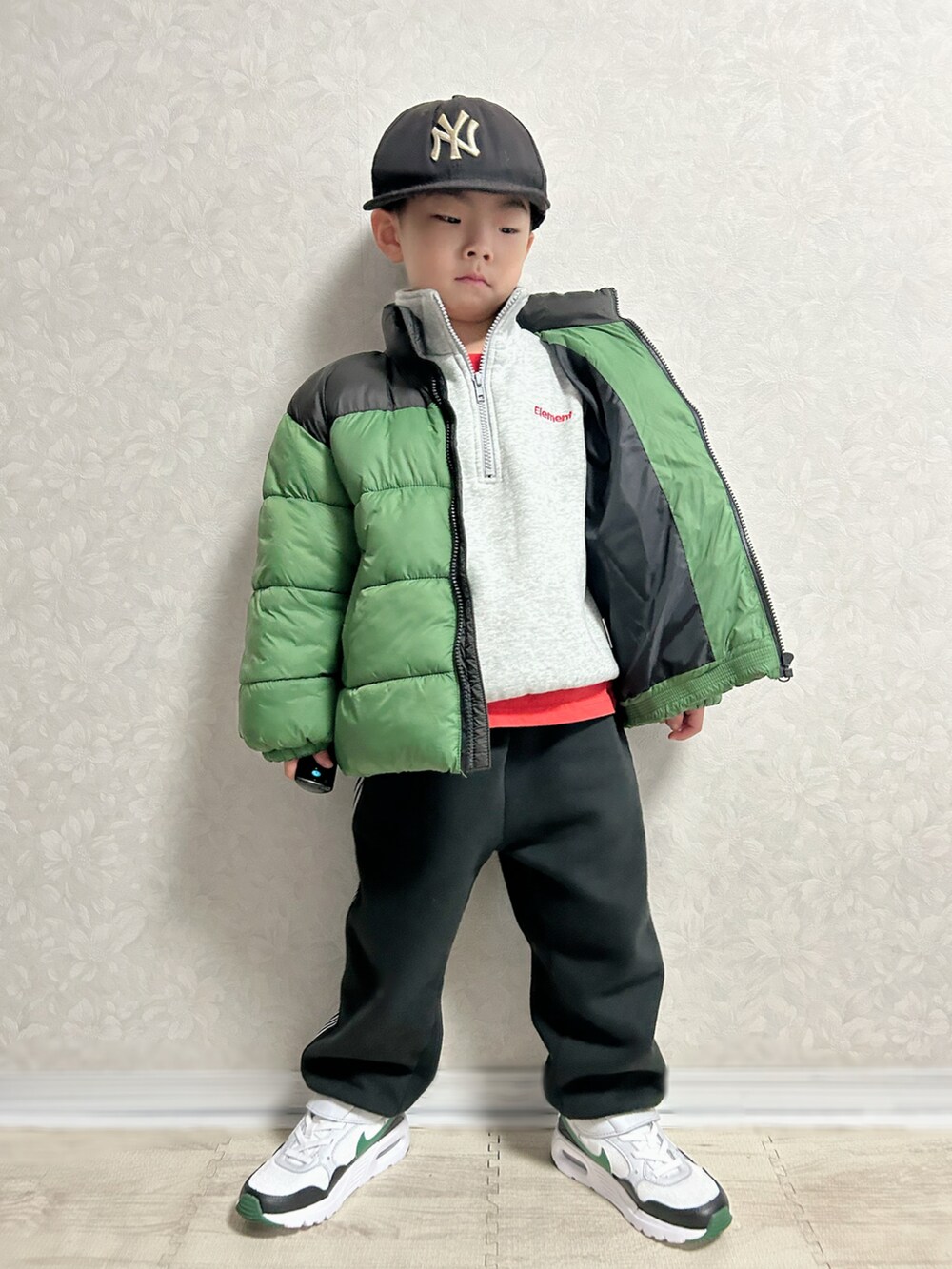 レッド系のTシャツ/カットソー、グレー系のスウェット、グリーン系のダウンジャケット/コートを着用したキッズの冬コーディネートの2枚目の写真