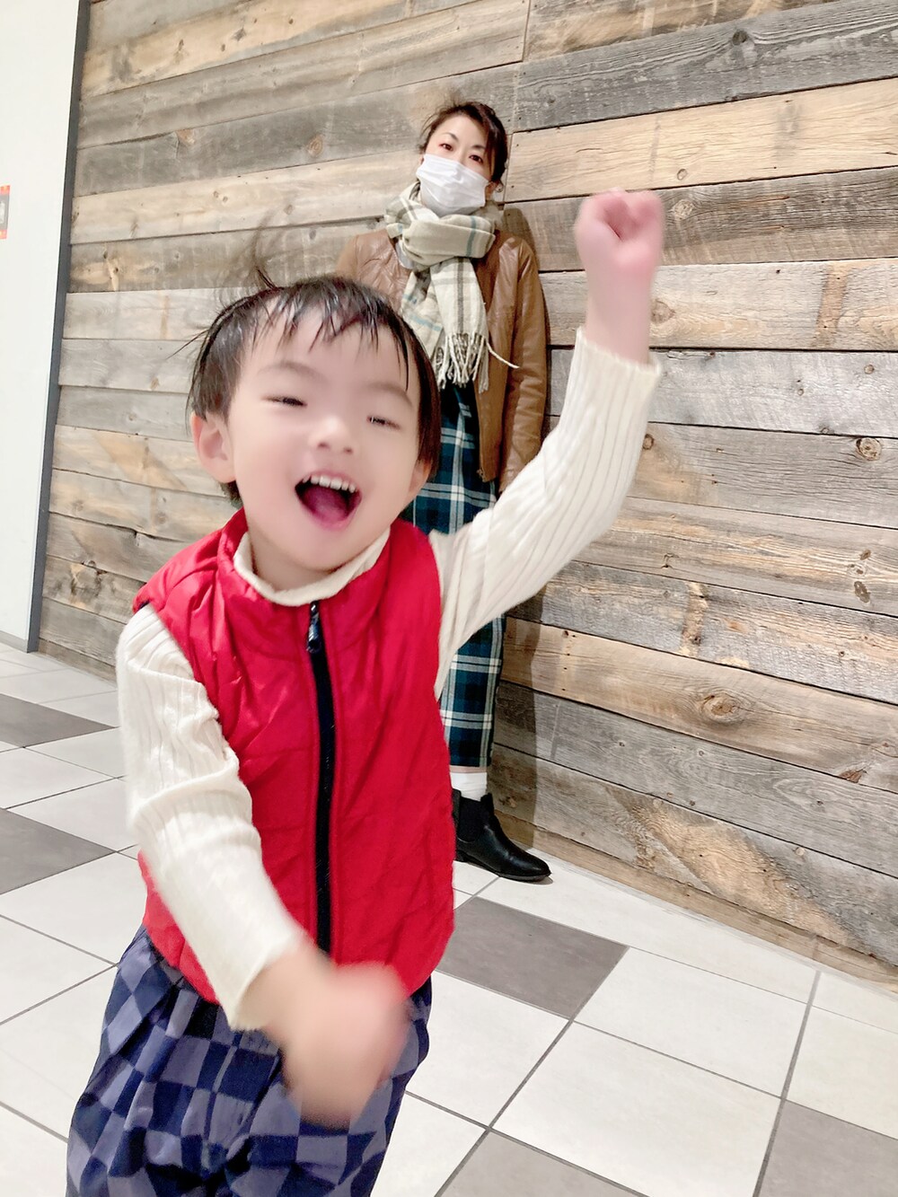 ブルー系のパンツ、レッド系のダウンベスト、ブラック系のブーツを着用したキッズの冬コーディネートの2枚目の写真