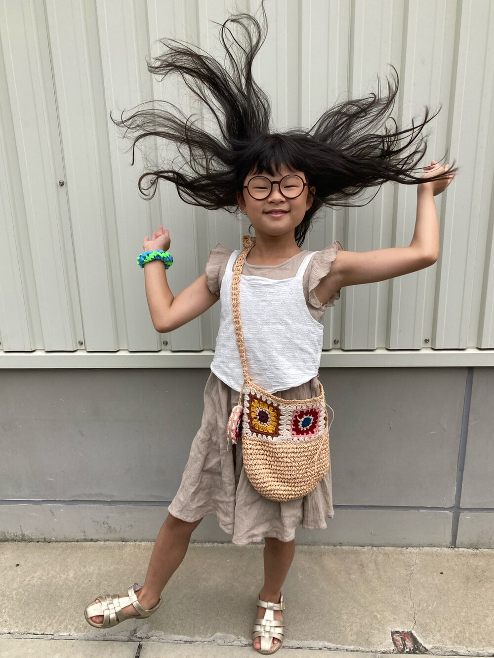 ベージュ系のワンピース、ホワイト系のキャミソール、ブラウン系のショルダーバッグを着用したキッズの夏コーディネートの2枚目の写真