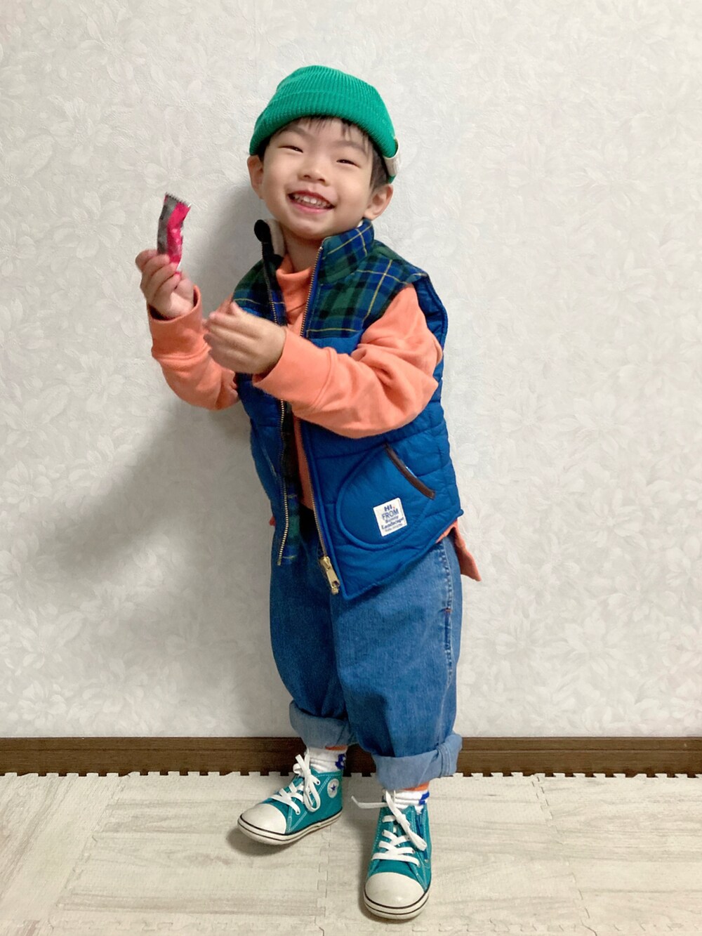 オレンジ系のスウェット、ブルー系のダウンベスト、ブルー系のデニムパンツを着用したキッズの冬コーディネートの3枚目の写真