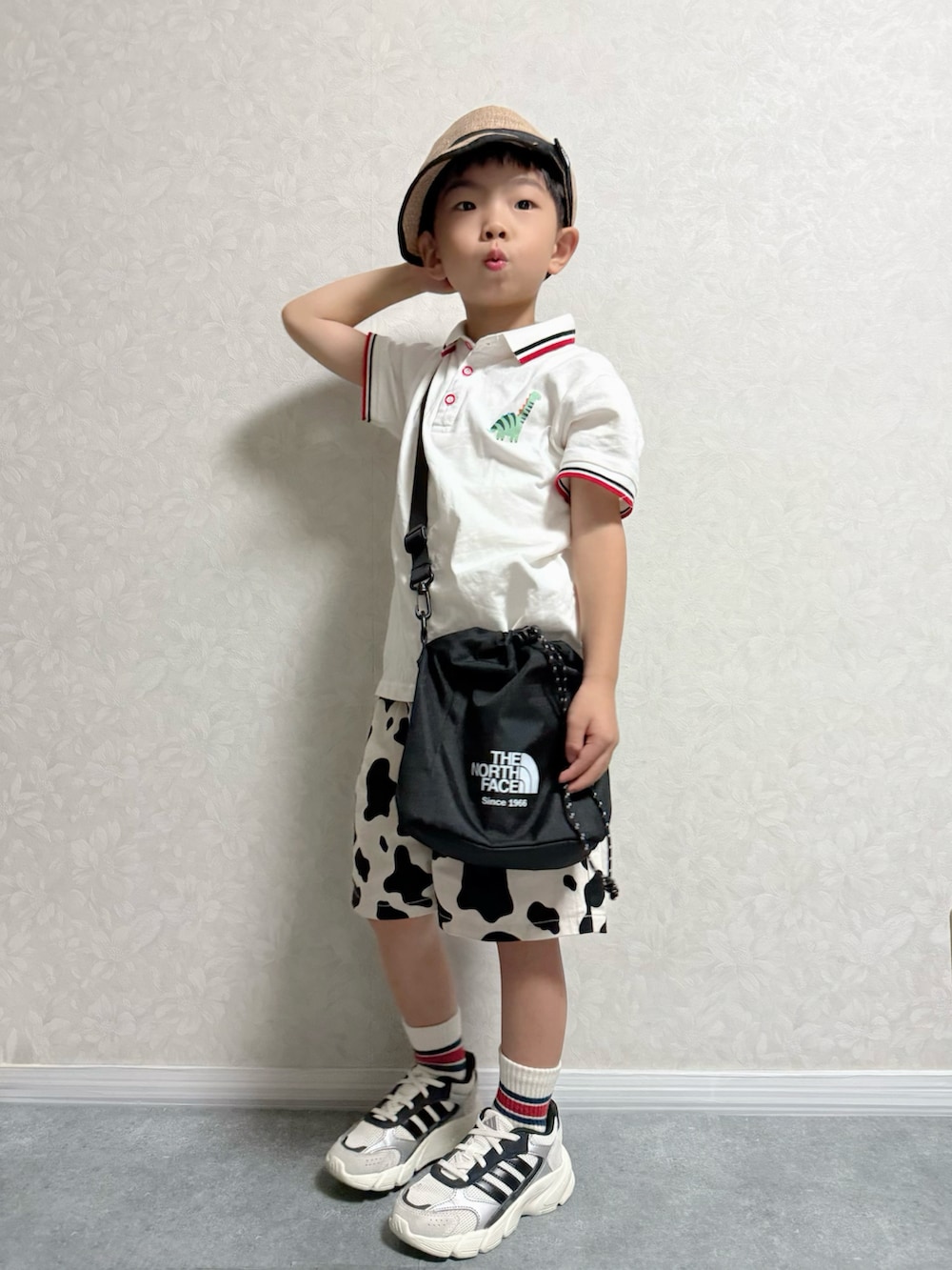 ホワイト系のポロシャツ、ブラック系のショルダーバッグ、ホワイト系のスニーカーを着用したキッズの秋コーディネートの2枚目の写真