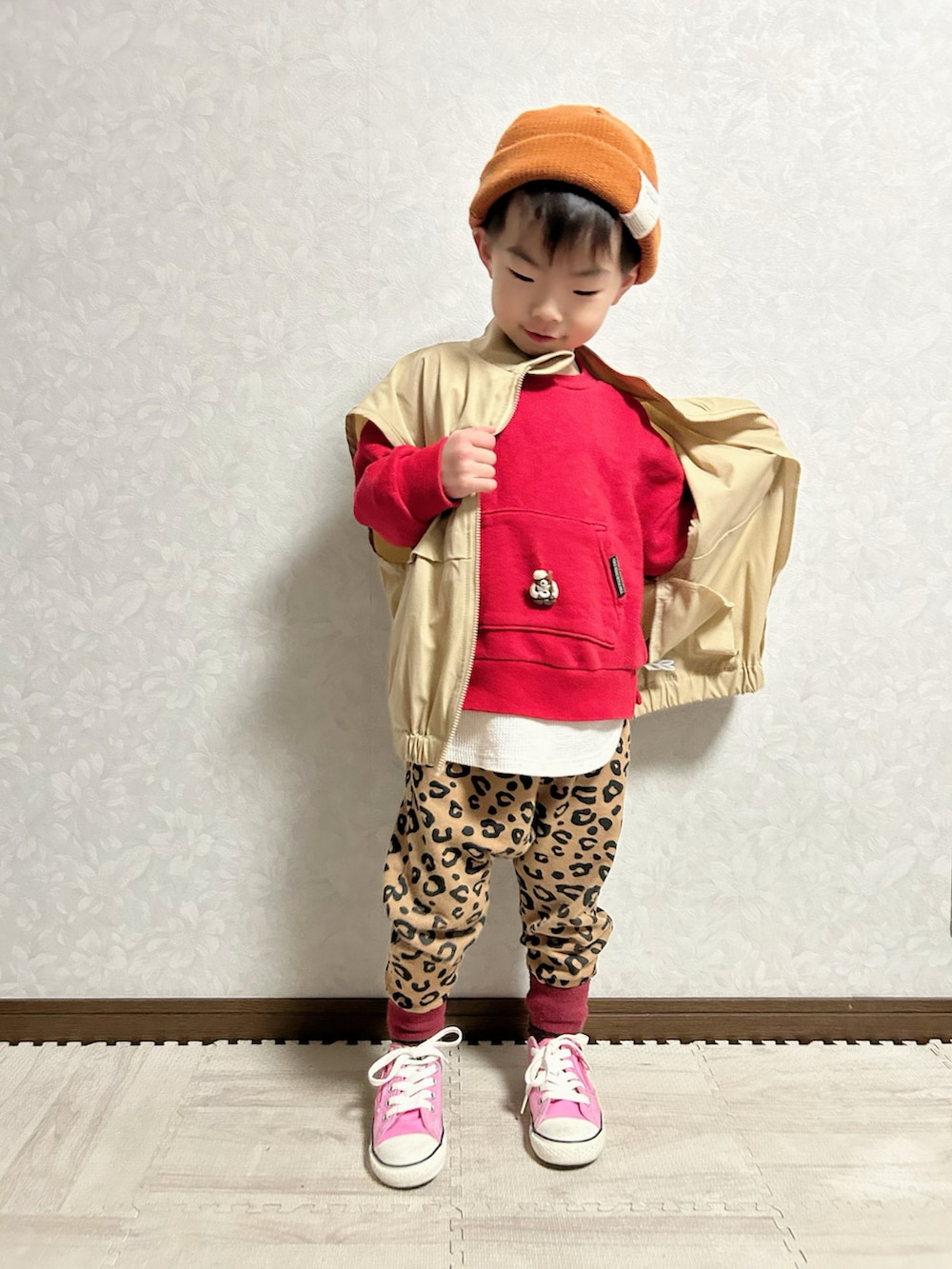 ベージュ系のベスト、レッド系のスウェット、ブラウン系のスウェットパンツを着用したキッズの冬コーディネートの2枚目の写真