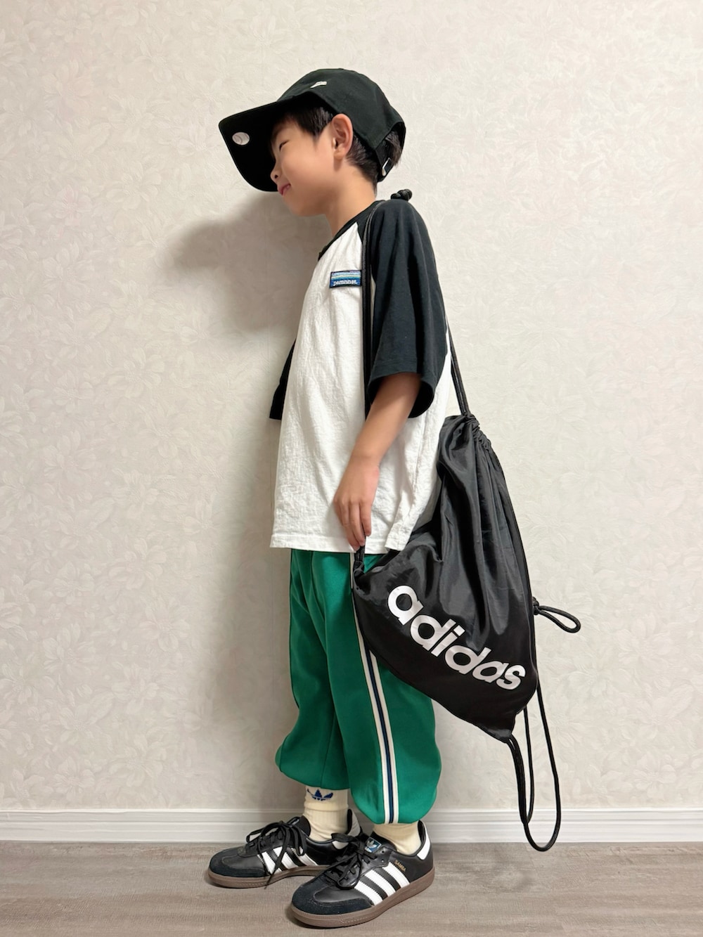 ホワイト系のTシャツ/カットソー、ブラック系のバックパック/リュック、グリーン系のスウェットパンツを着用したキッズの秋コーディネートの3枚目の写真