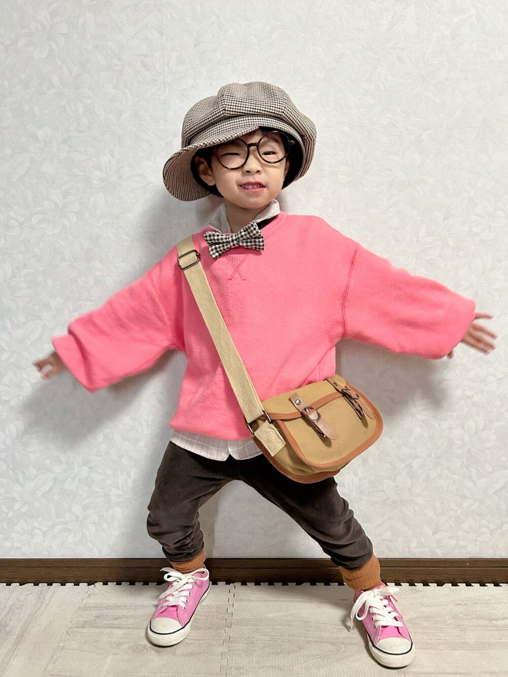 ピンク系のニット/セーター、ベージュ系のセットアップ、ブラウン系のショルダーバッグを着用したキッズの冬コーディネートの2枚目の写真