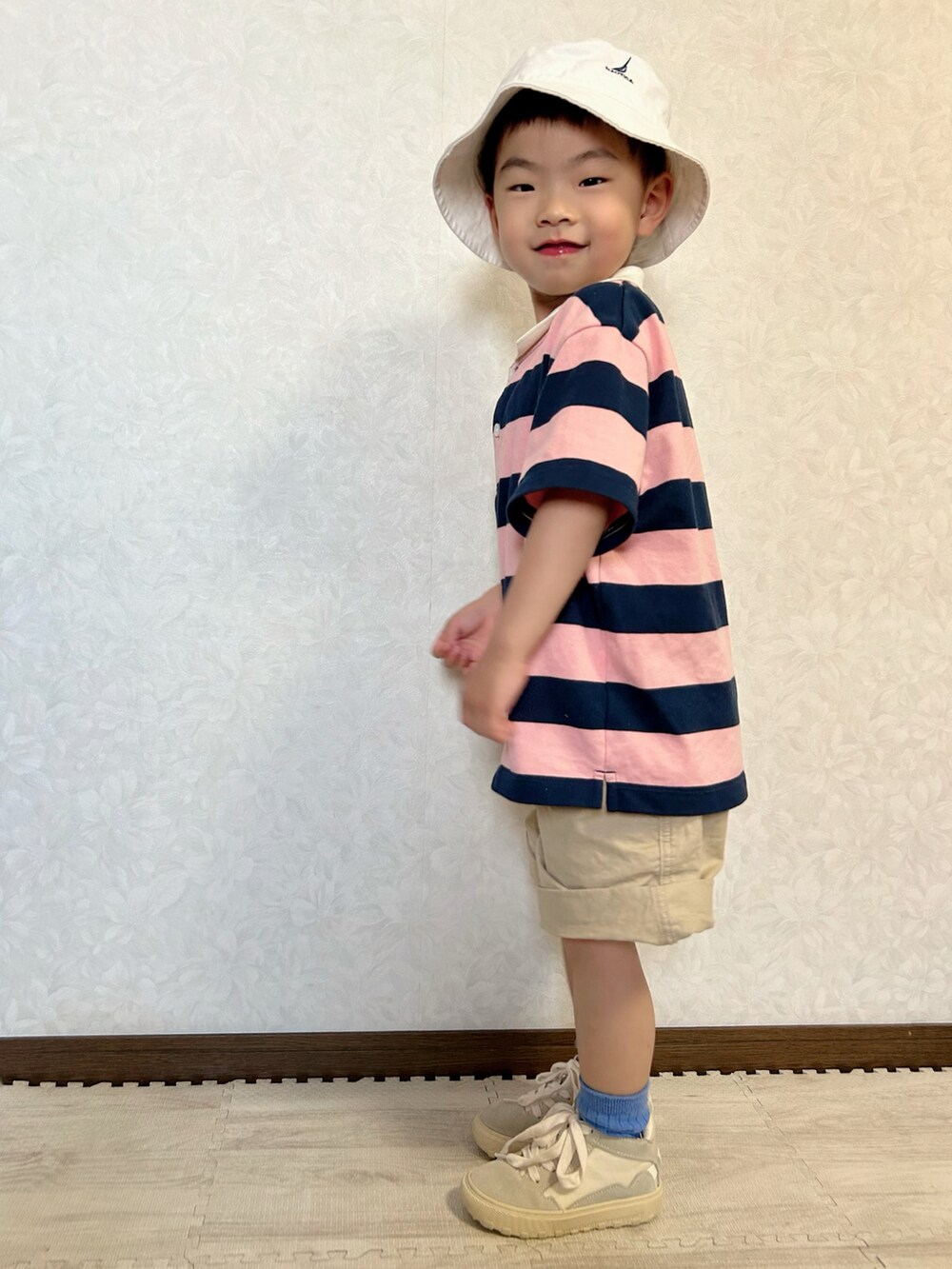 ピンク系のポロシャツ、ベージュ系のチノパンツ、ホワイト系のスニーカーを着用したキッズの春コーディネートの2枚目の写真