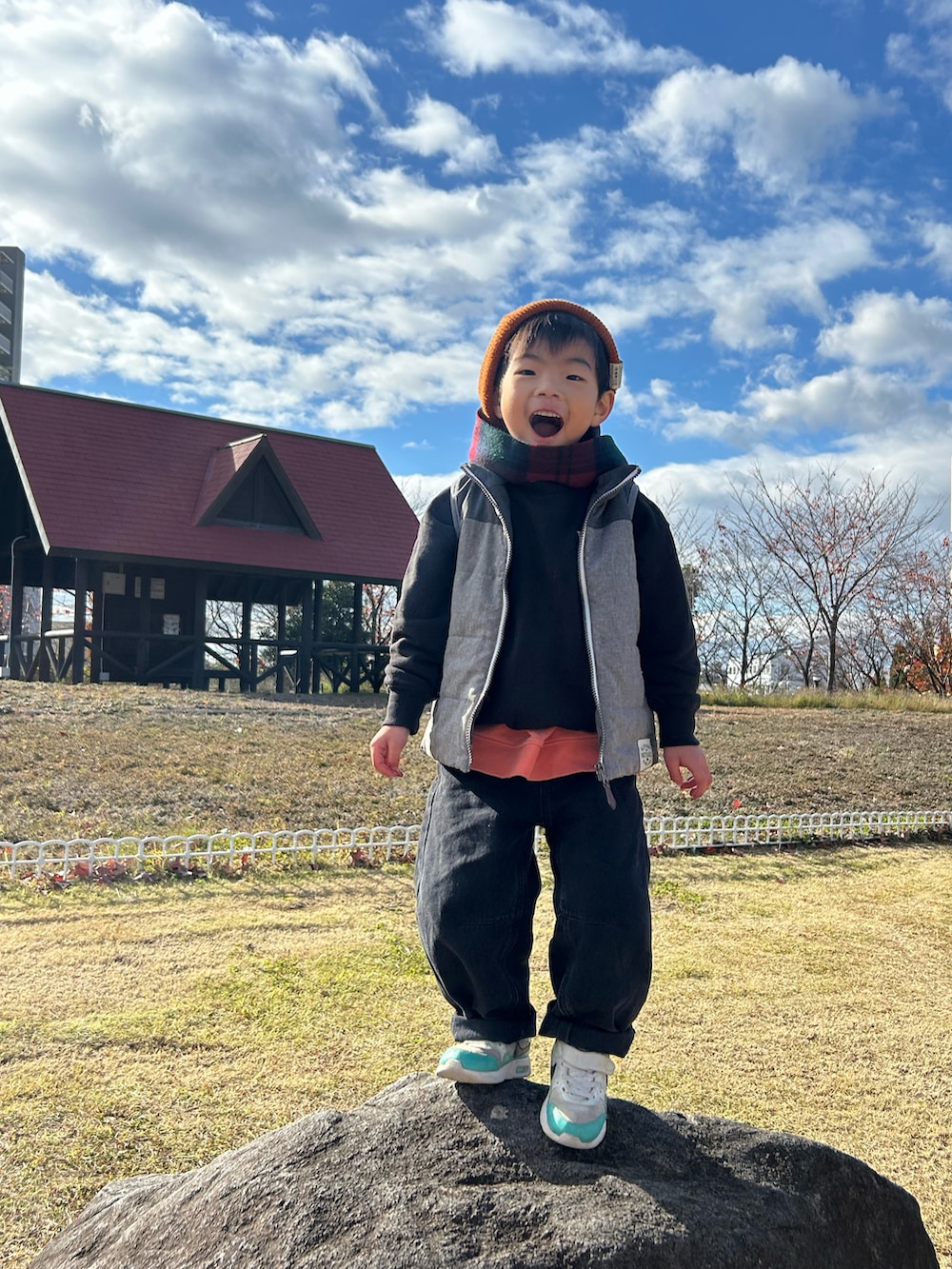 オレンジ系のスウェット、グレー系のスウェット、グレー系のダウンベストを着用したキッズの冬コーディネートの3枚目の写真