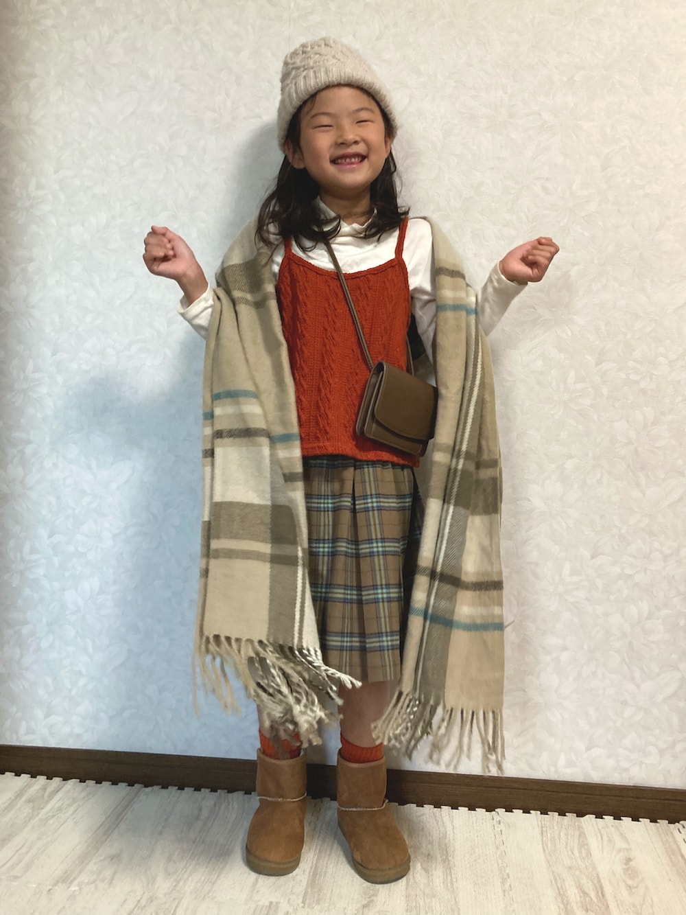 ホワイト系のTシャツ/カットソー、オレンジ系のベスト、ブラウン系のスカートを着用したキッズの秋コーディネートの2枚目の写真