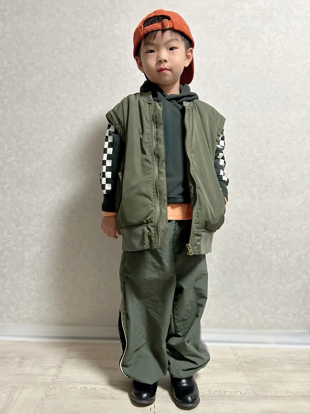 オレンジ系のTシャツ/カットソー、ブラック系のパーカー、グリーン系のMA-1を着用したキッズの秋コーディネートの2枚目の写真