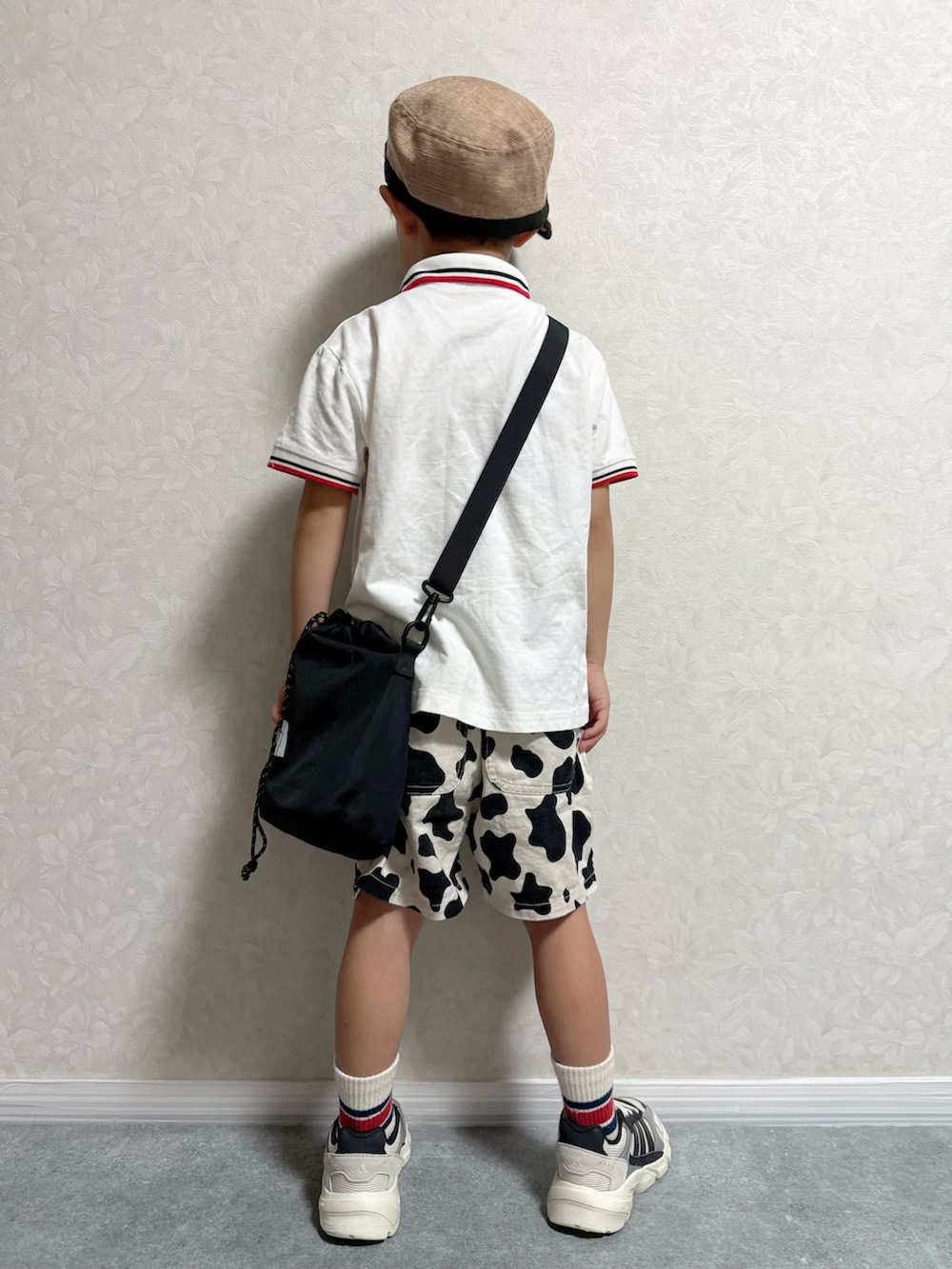 ホワイト系のポロシャツ、ブラック系のショルダーバッグ、ホワイト系のスニーカーを着用したキッズの秋コーディネートの4枚目の写真