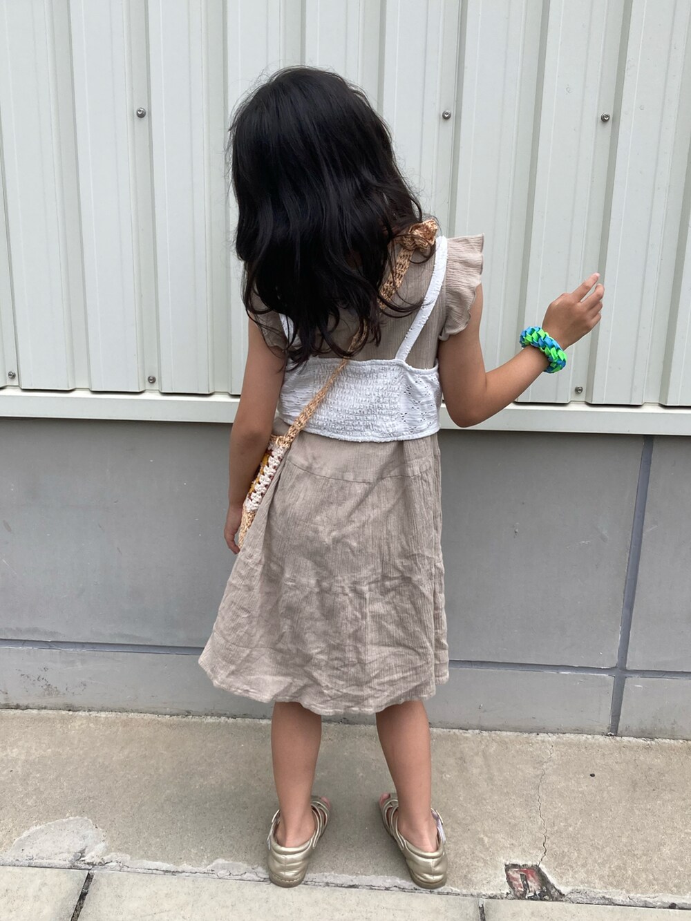 ベージュ系のワンピース、ホワイト系のキャミソール、ブラウン系のショルダーバッグを着用したキッズの夏コーディネートの4枚目の写真