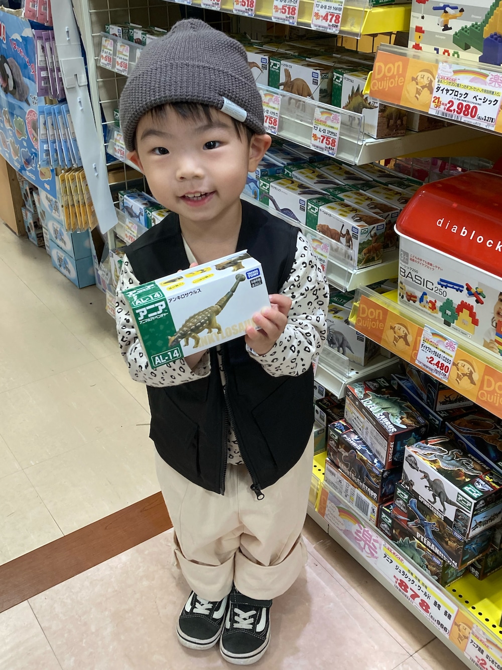 ベージュ系のTシャツ/カットソー、ブラック系のベスト、ベージュ系のチノパンツを着用したキッズの秋コーディネートの2枚目の写真