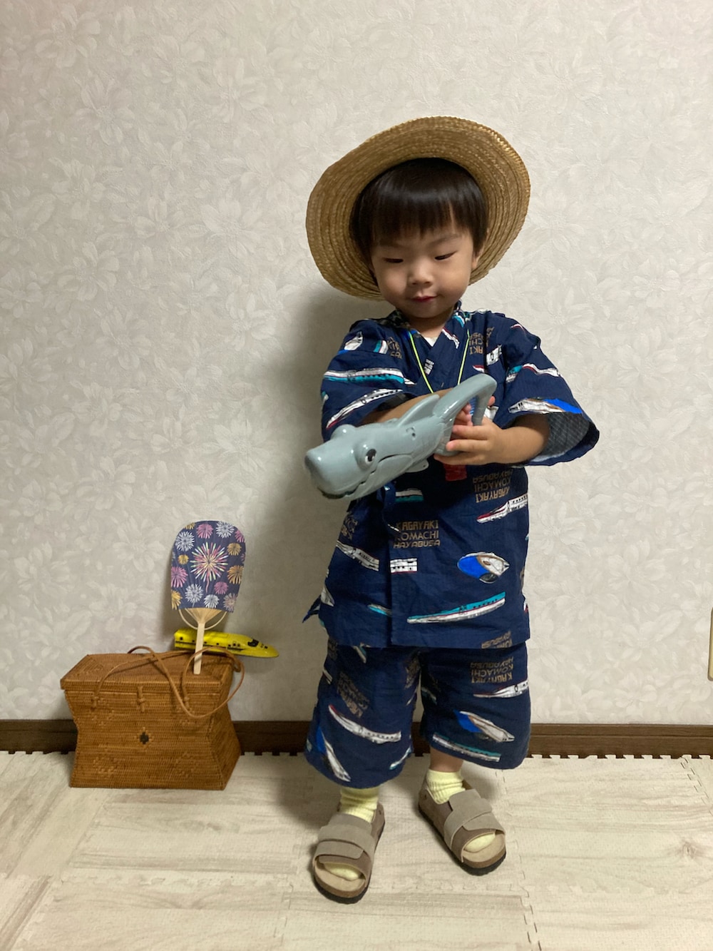 ベージュ系のサンダル、ブラウン系のかごバッグ、ベージュ系のハットを着用したキッズの夏コーディネートの3枚目の写真