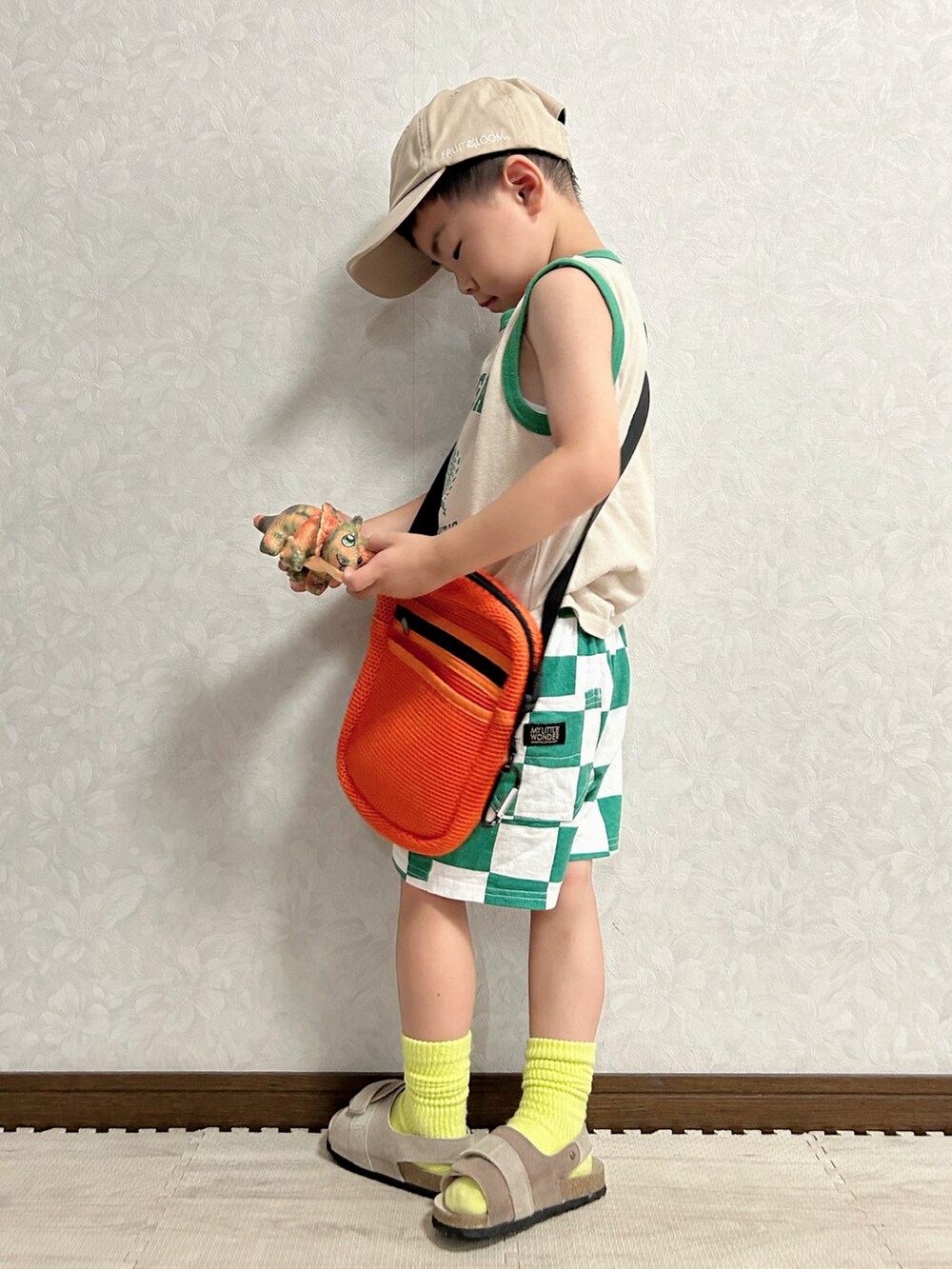 ベージュ系のタンクトップ、グリーン系のパンツ、オレンジ系のショルダーバッグを着用したキッズの夏コーディネートの3枚目の写真