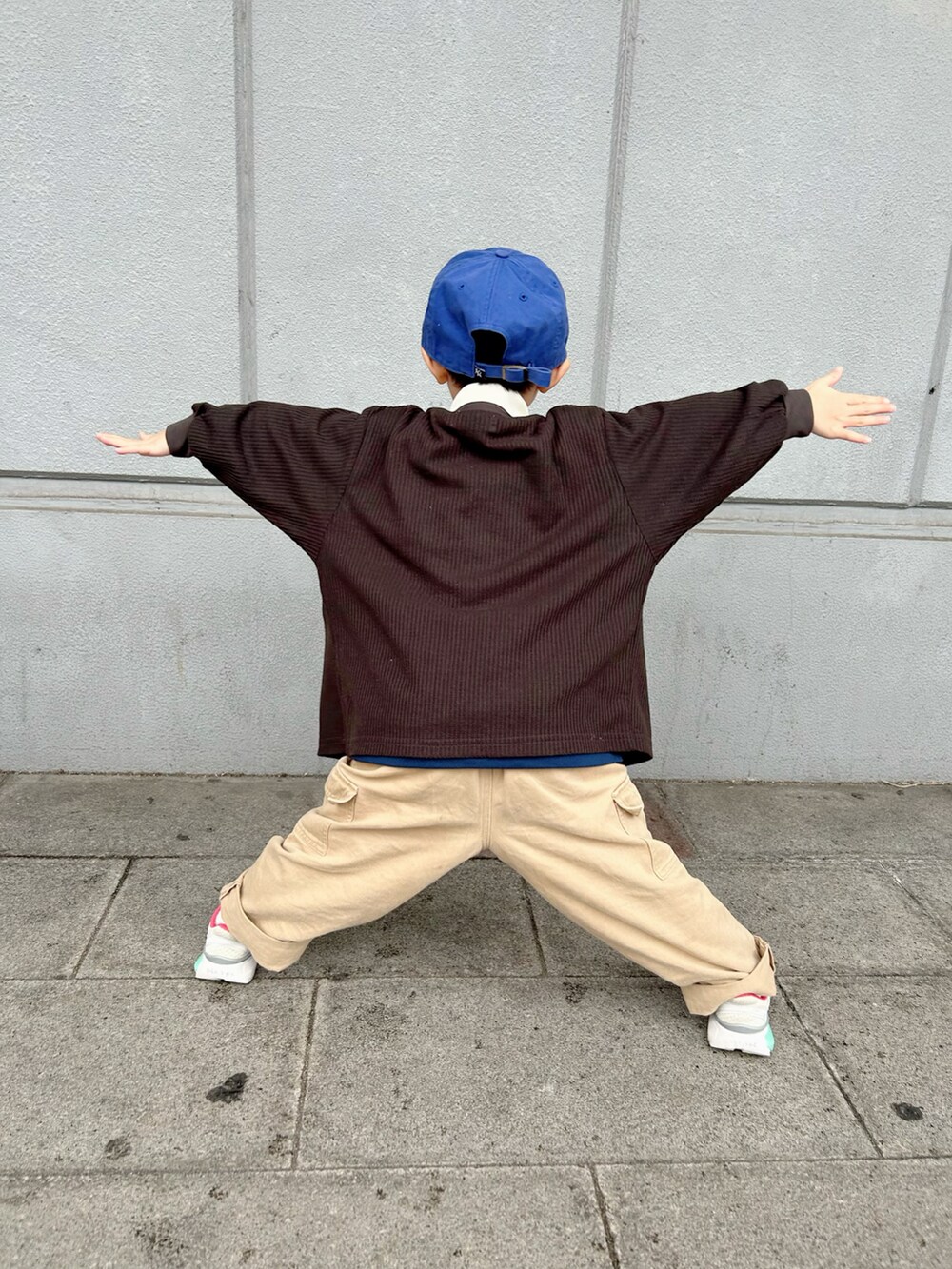 ピンク系のポロシャツ、ブラック系のカーディガン/ボレロ、ベージュ系のカーゴパンツを着用したキッズの冬コーディネートの3枚目の写真